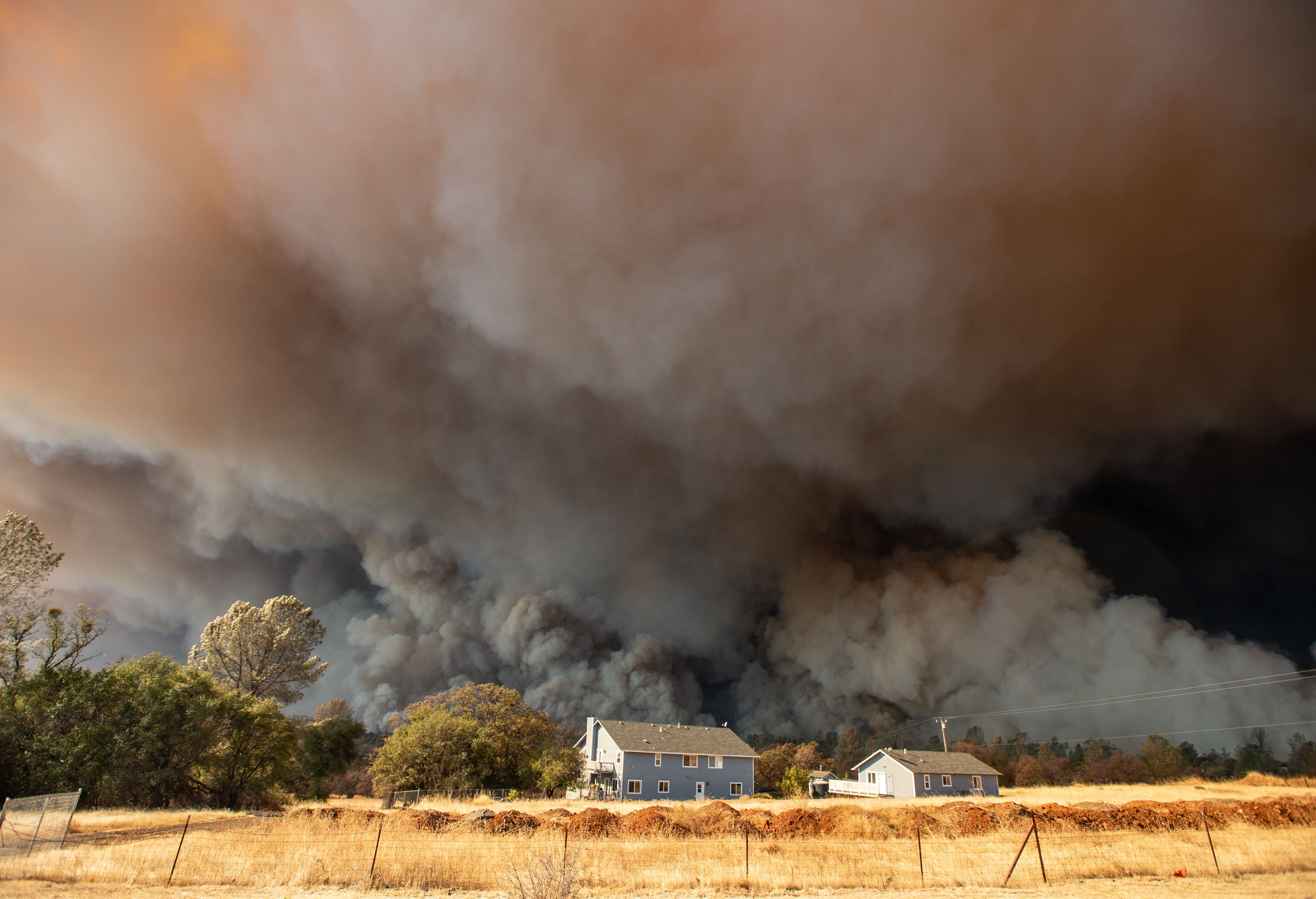 Smoke plumes from the Camp Fire tower over homes in Paradise