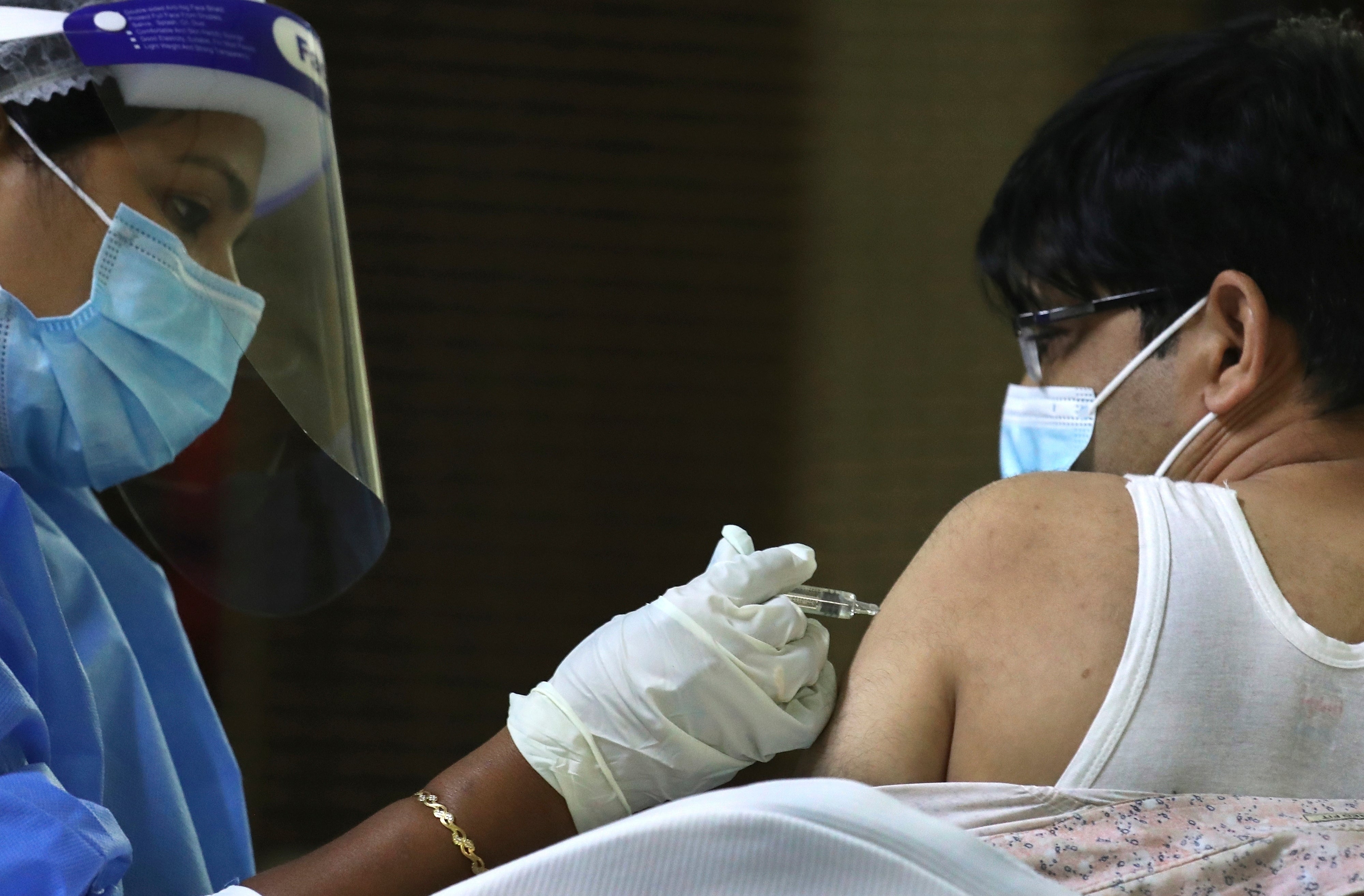 A man receives a Covid vaccine from a medical staffer at Guru Nanak Darbar temple in Dubai, United Arab Emirates