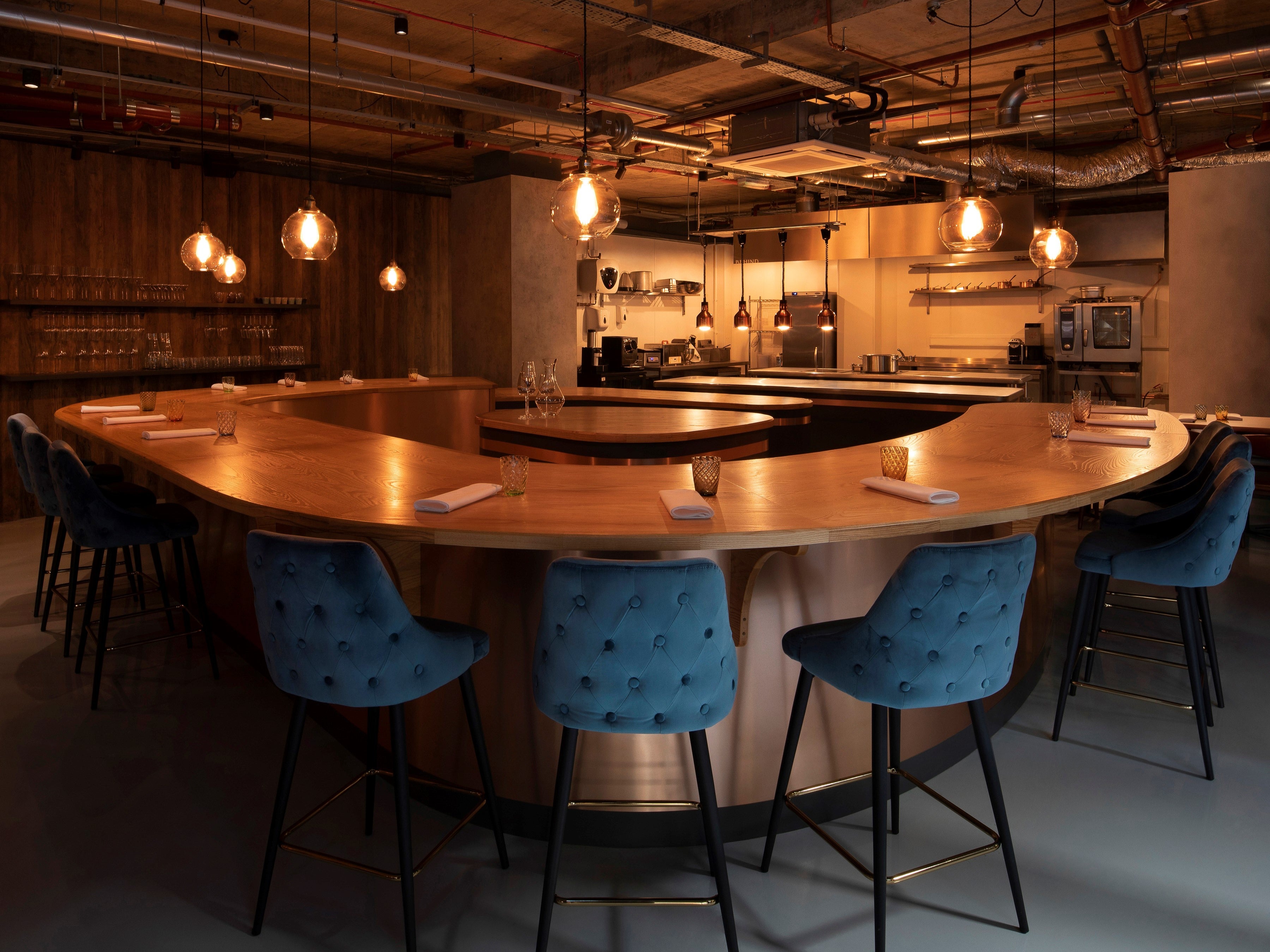 Seating is arranged in a semi-circle shape, with the kitchen acting as the focal point of the restaurant