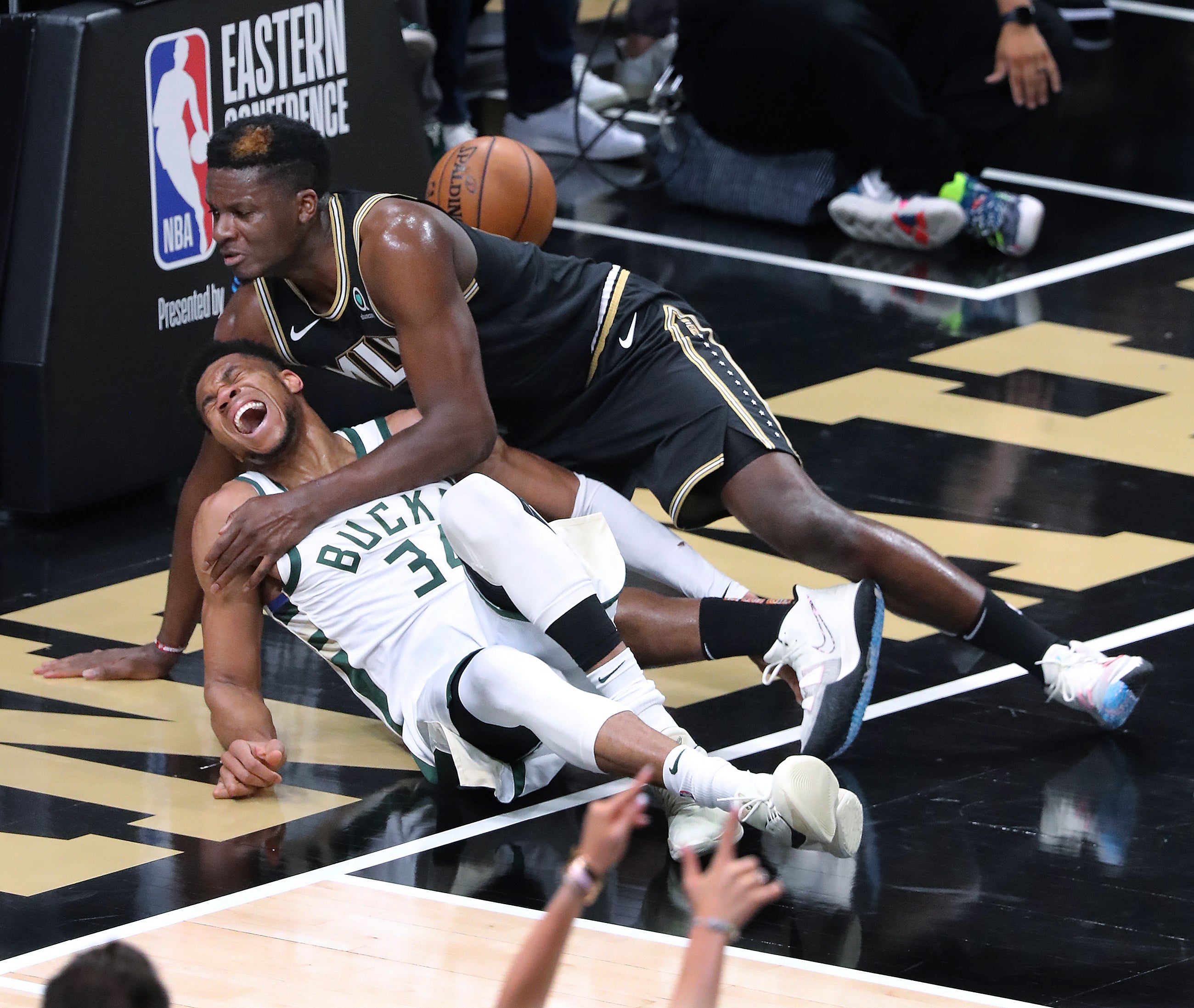 Atlanta Hawks center Clint Capela, top, and Milwaukee Bucks forward Giannis Antetokounmpo fall to the court