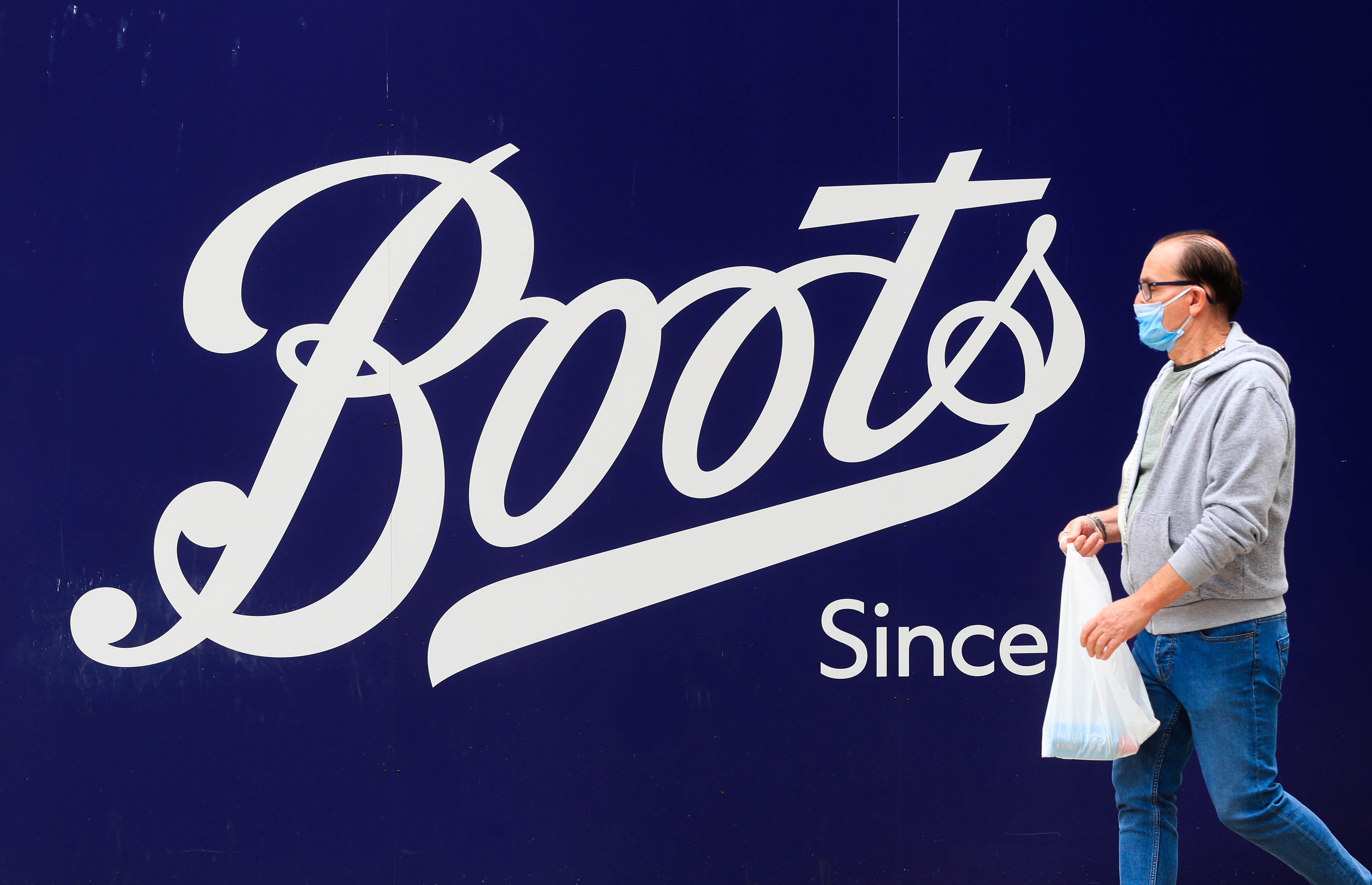 A man walks past a Boots sign