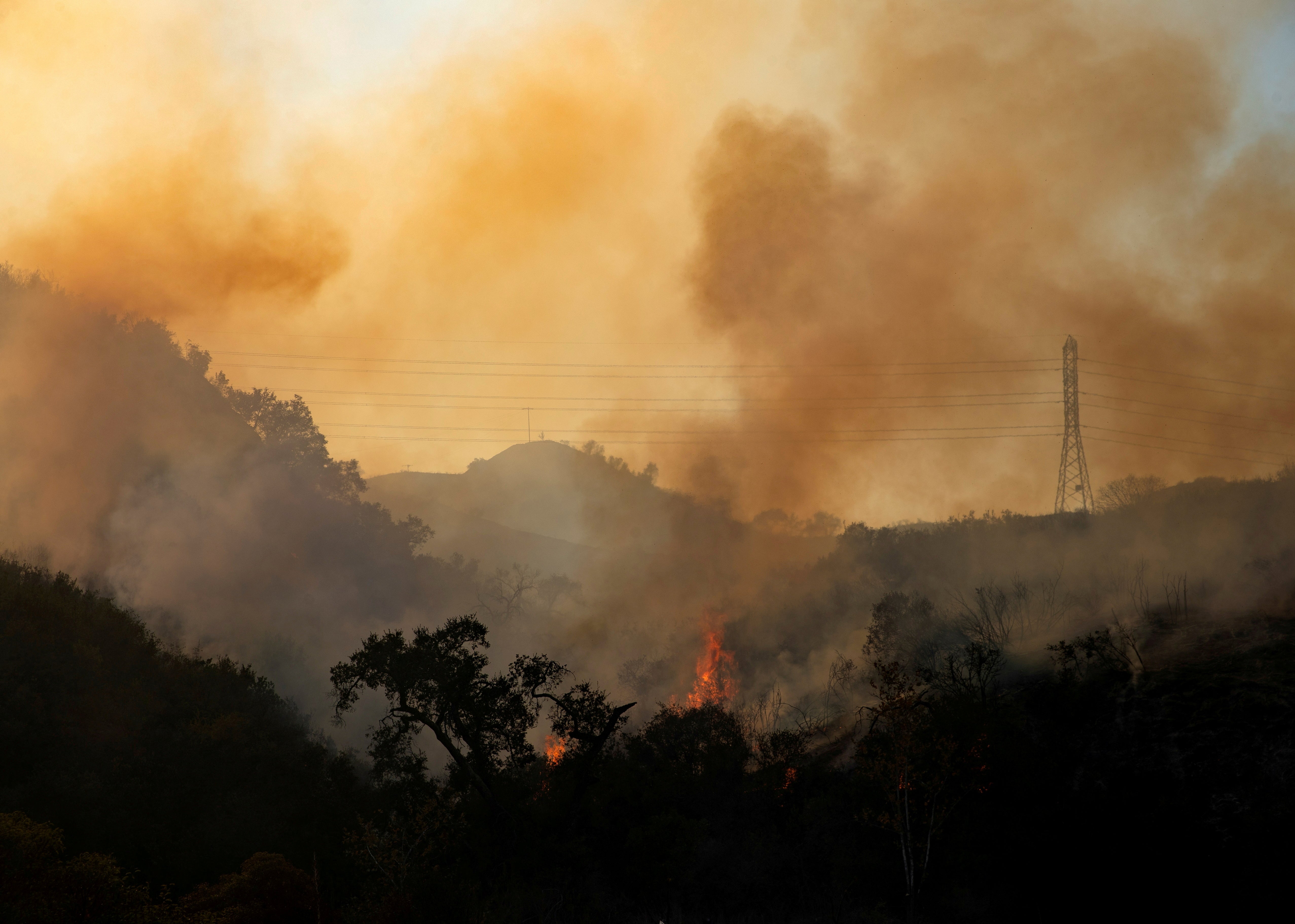 The Bond Fire wildfire continues to burn next to electrical power lines near Modjeska Canyon, California