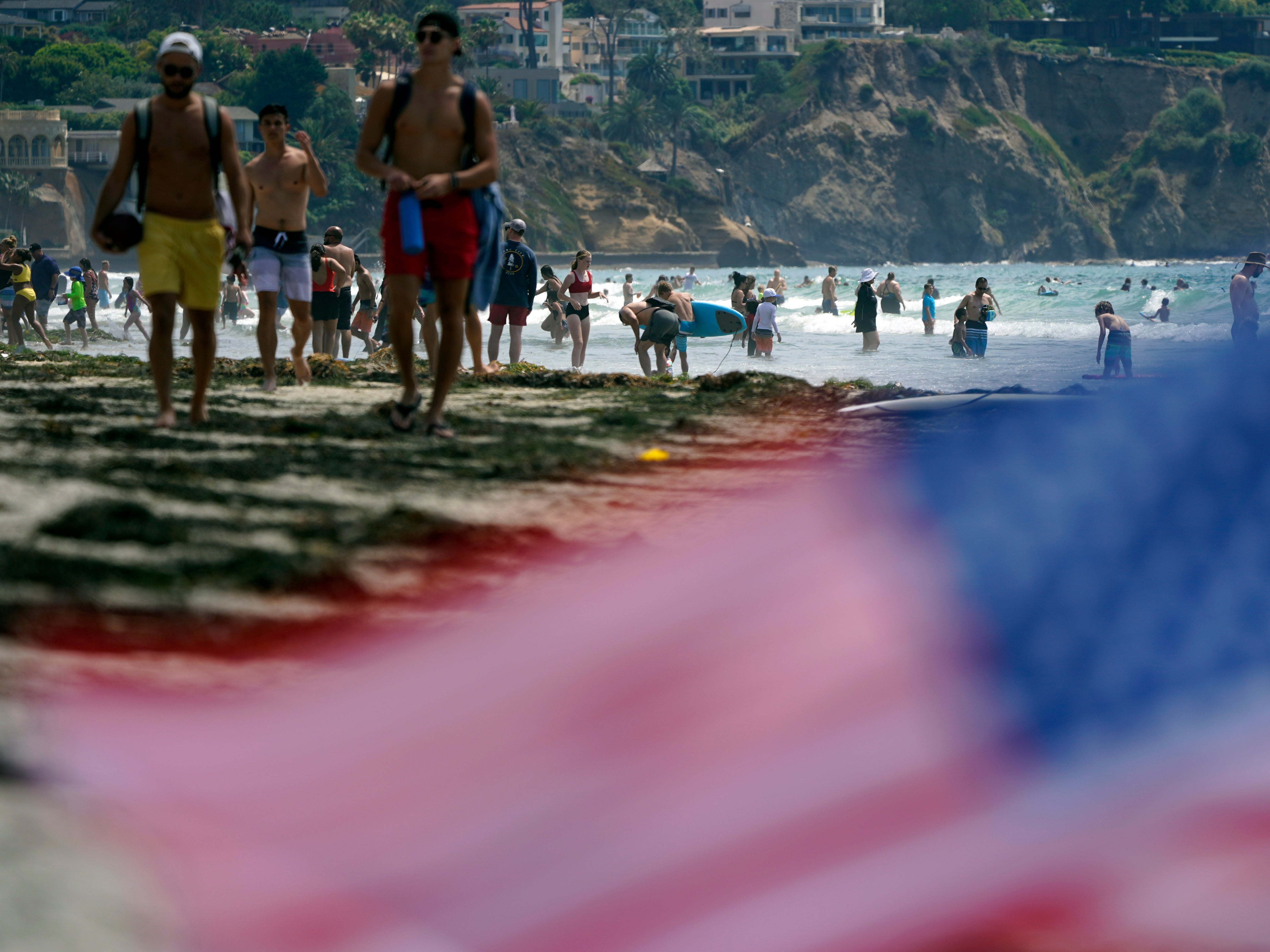 FILE - In this July 1, 2021, file photo, people walk along La Jolla Shores beach as Independence Day weekend nears in San Diego. Americans enjoying newfound liberty are expected to travel and gather for cookouts, fireworks and family reunions over the Fourth of July weekend in numbers not seen since pre-pandemic days. (AP Photo/Gregory Bull, File)