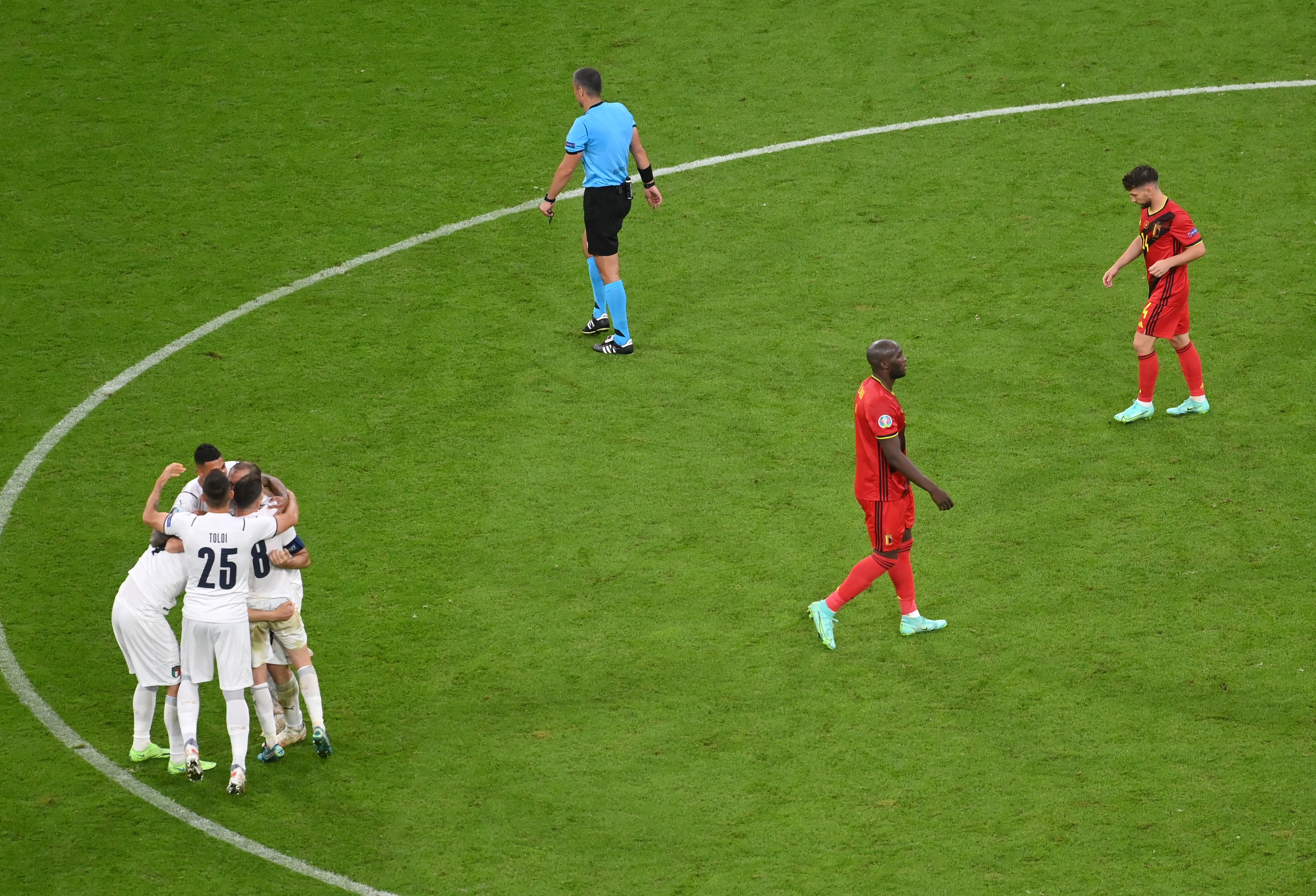 Players of Italy celebrate their side's victory as Romelu Lukaku and Dries Mertens of Belgium look dejected