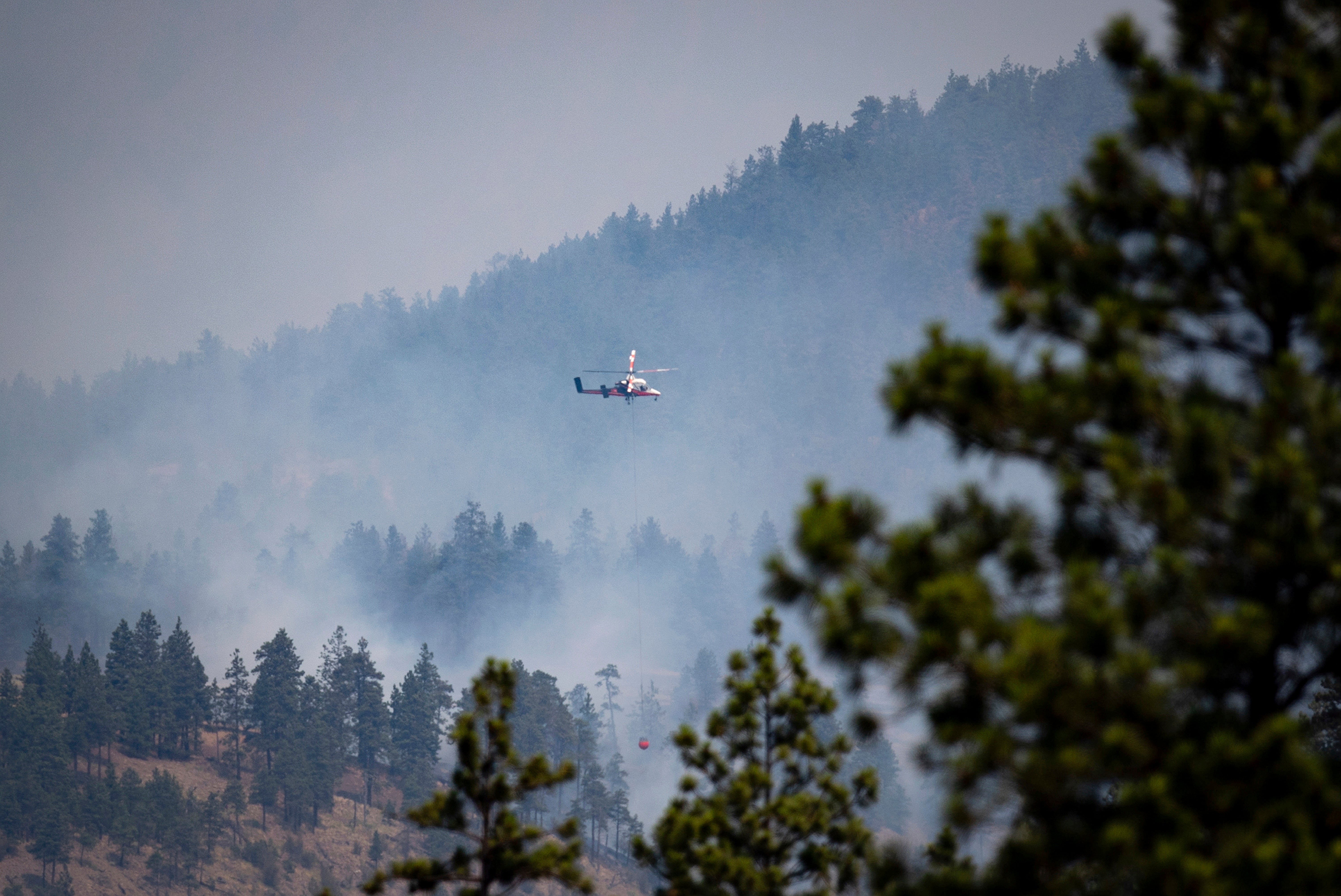 A helicopter prepares to drop water on a wildfire burning in Lytton