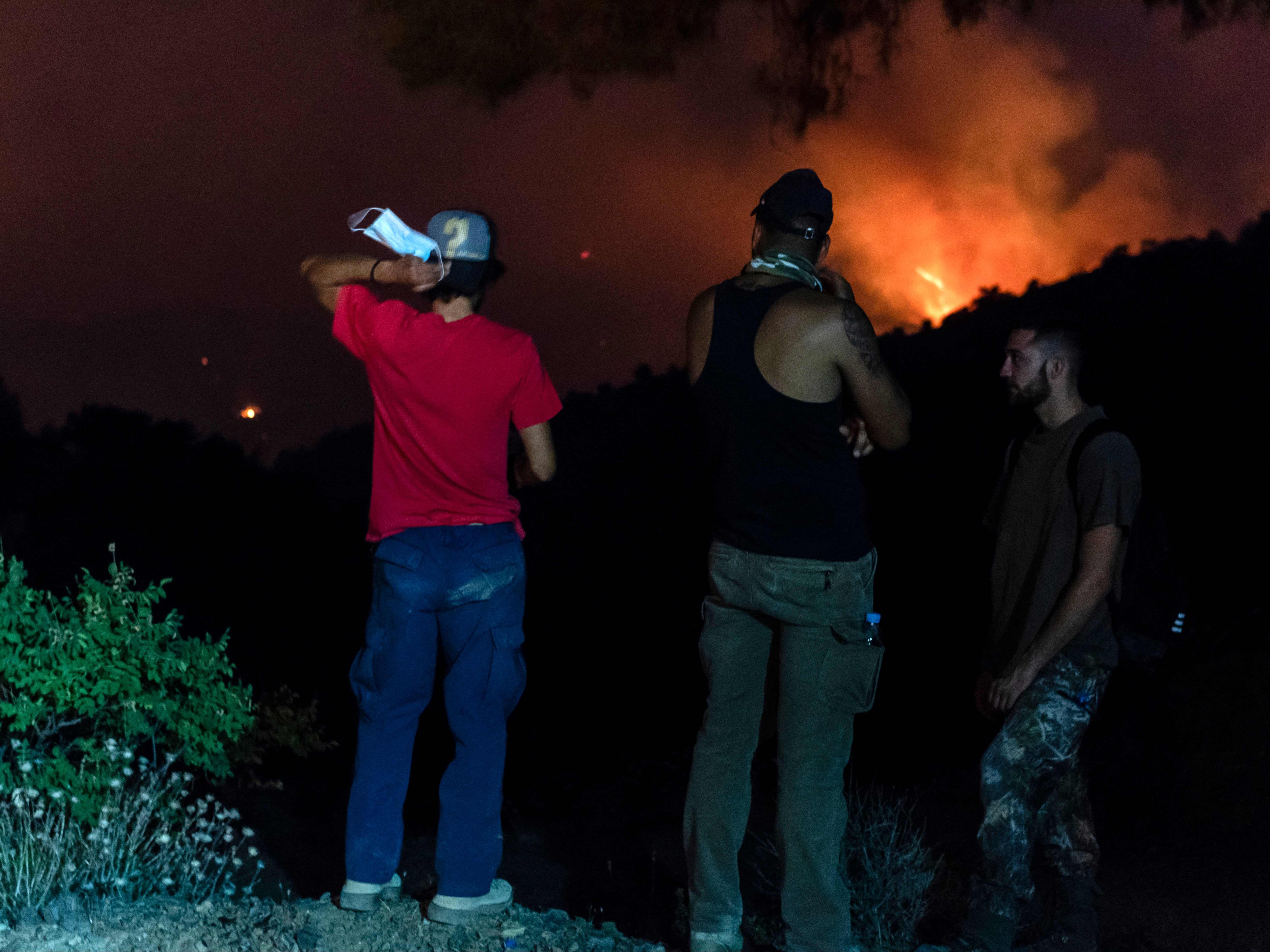 People in the village of Vavatsina watch as the wildfire rages on nearby hills