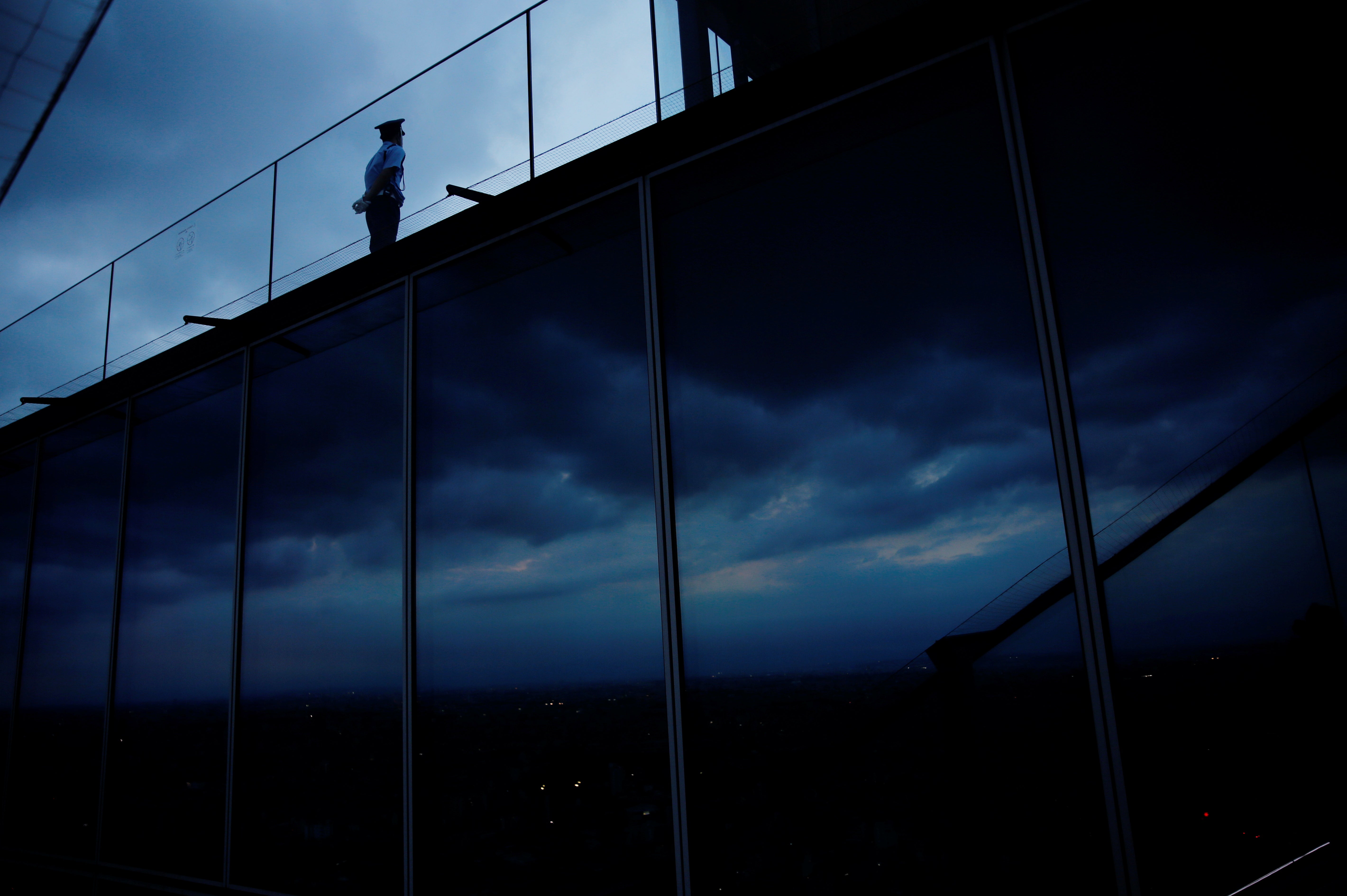 A guard stands on Shibuya Sky, the observation deck of Shibuya Scramble Square, during sunset in Tokyo