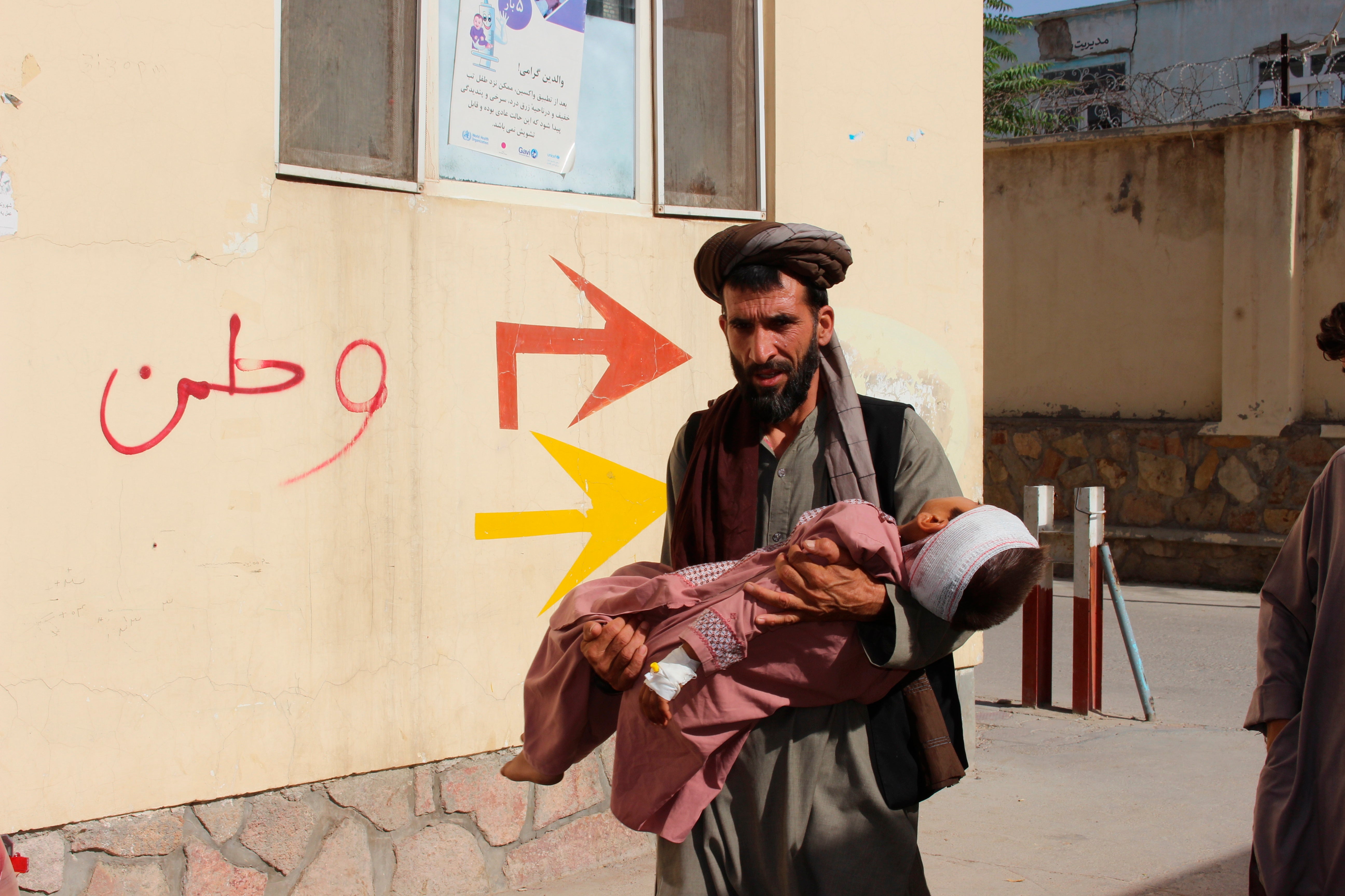 An Afghan civilian carry a wounded child to the hospital after he was injured during fighting between Taliban and government in Badghis province, northwest of Afghanistan