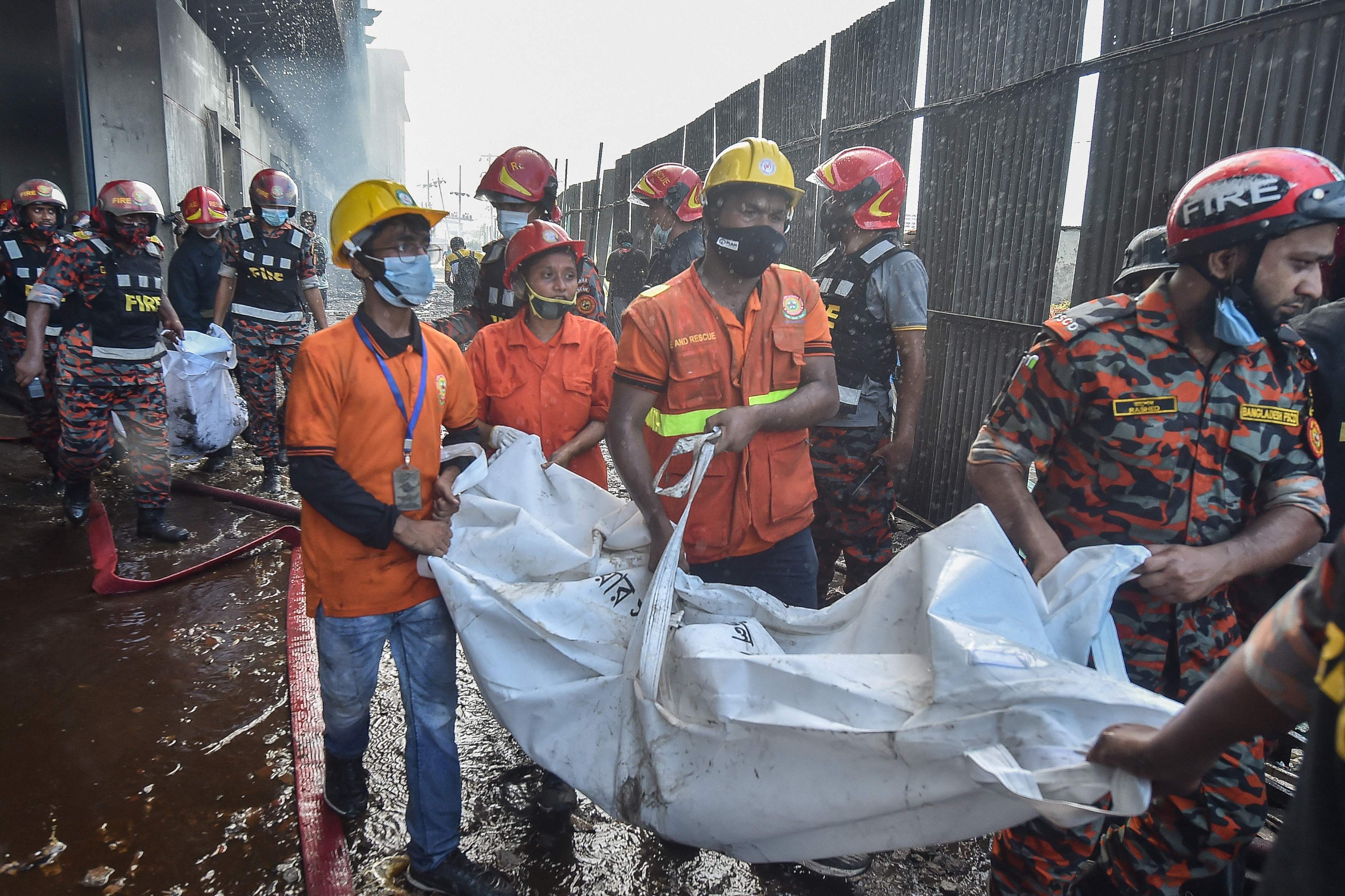 Firefighters and rescue workers recover bodies of the deceased who died in the fire