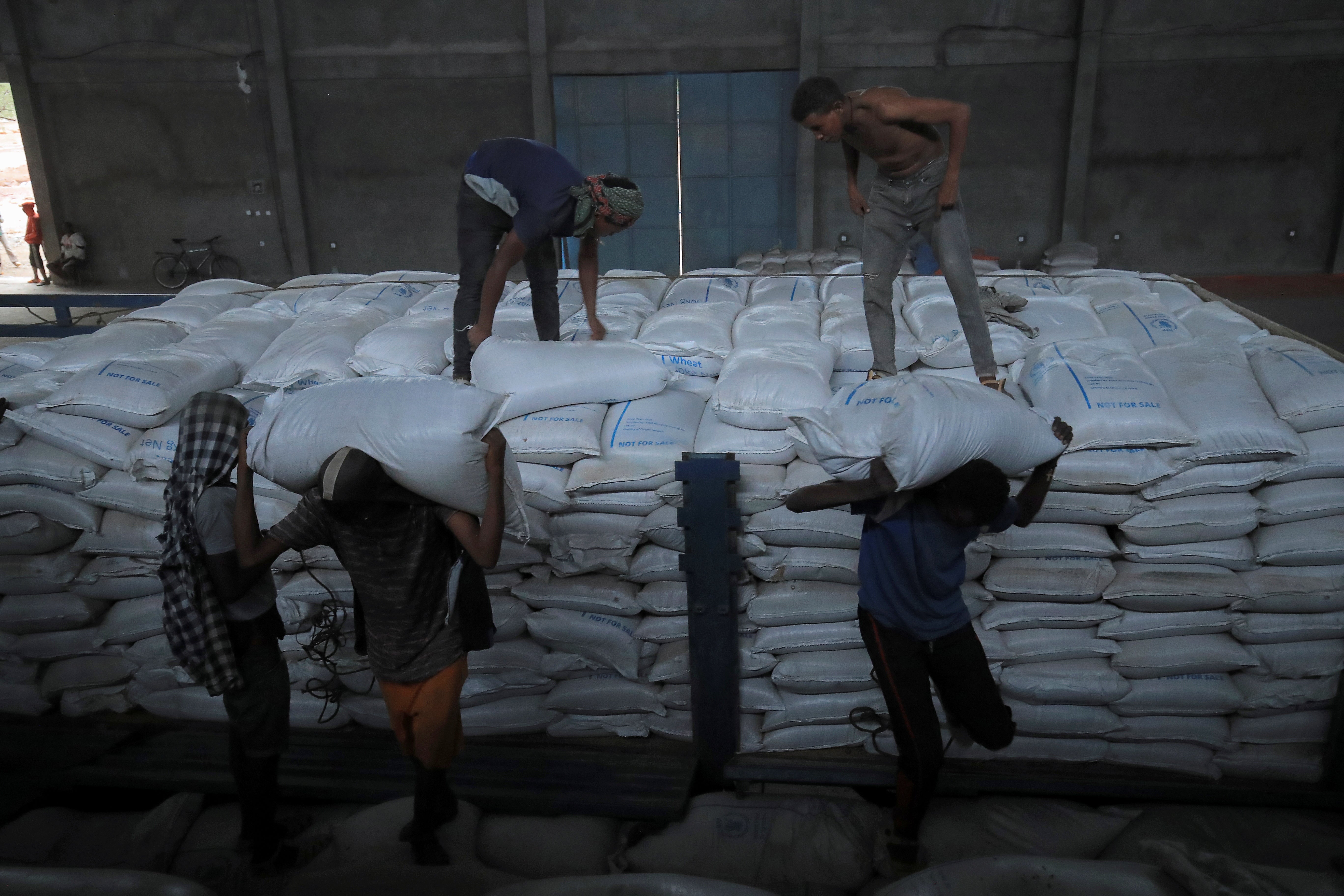 Ethiopian porters unload food aid bound for victims of war after a checkpoint leading to Tigray in Mai Tsebri town