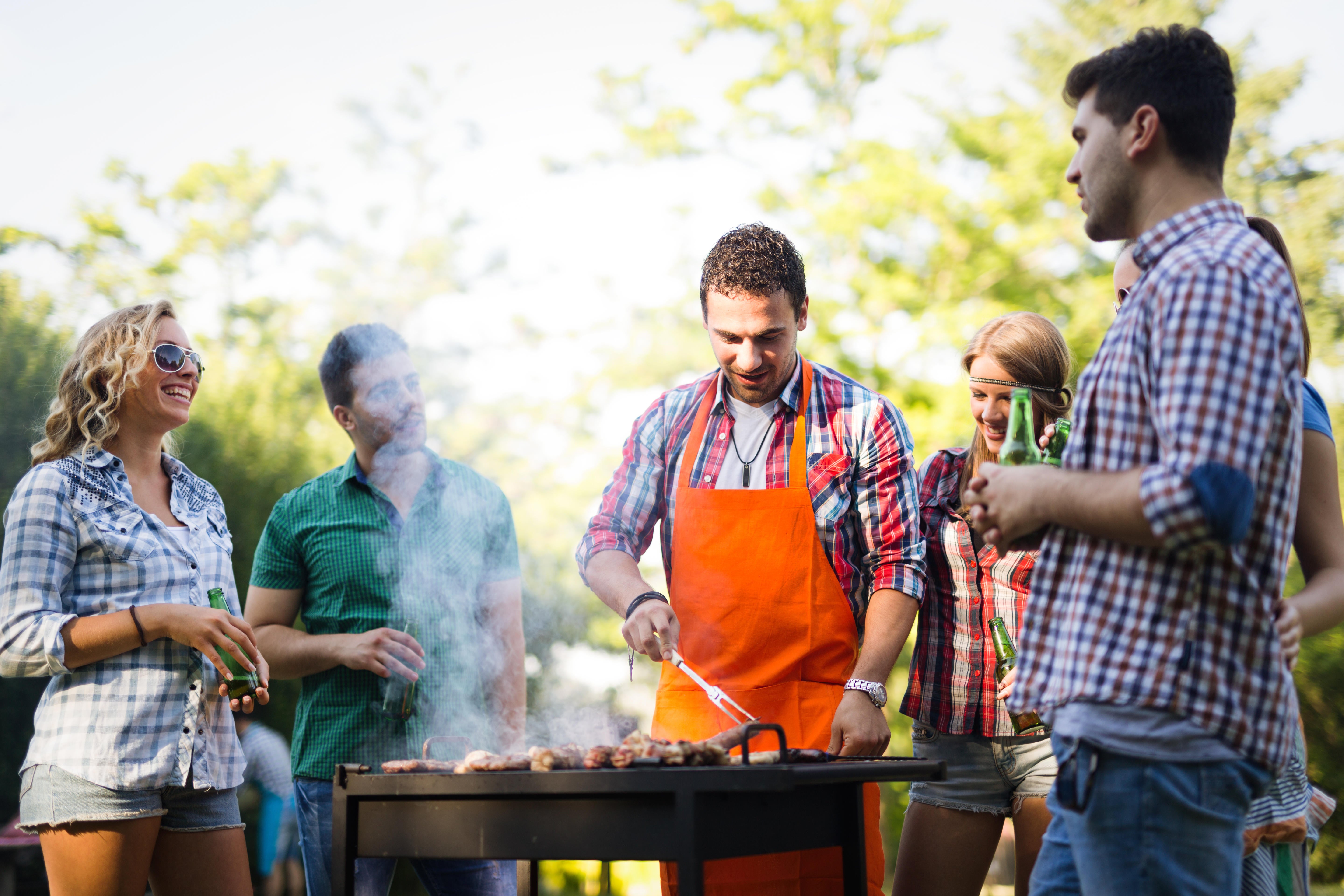 Happy students having barbecue on summer day