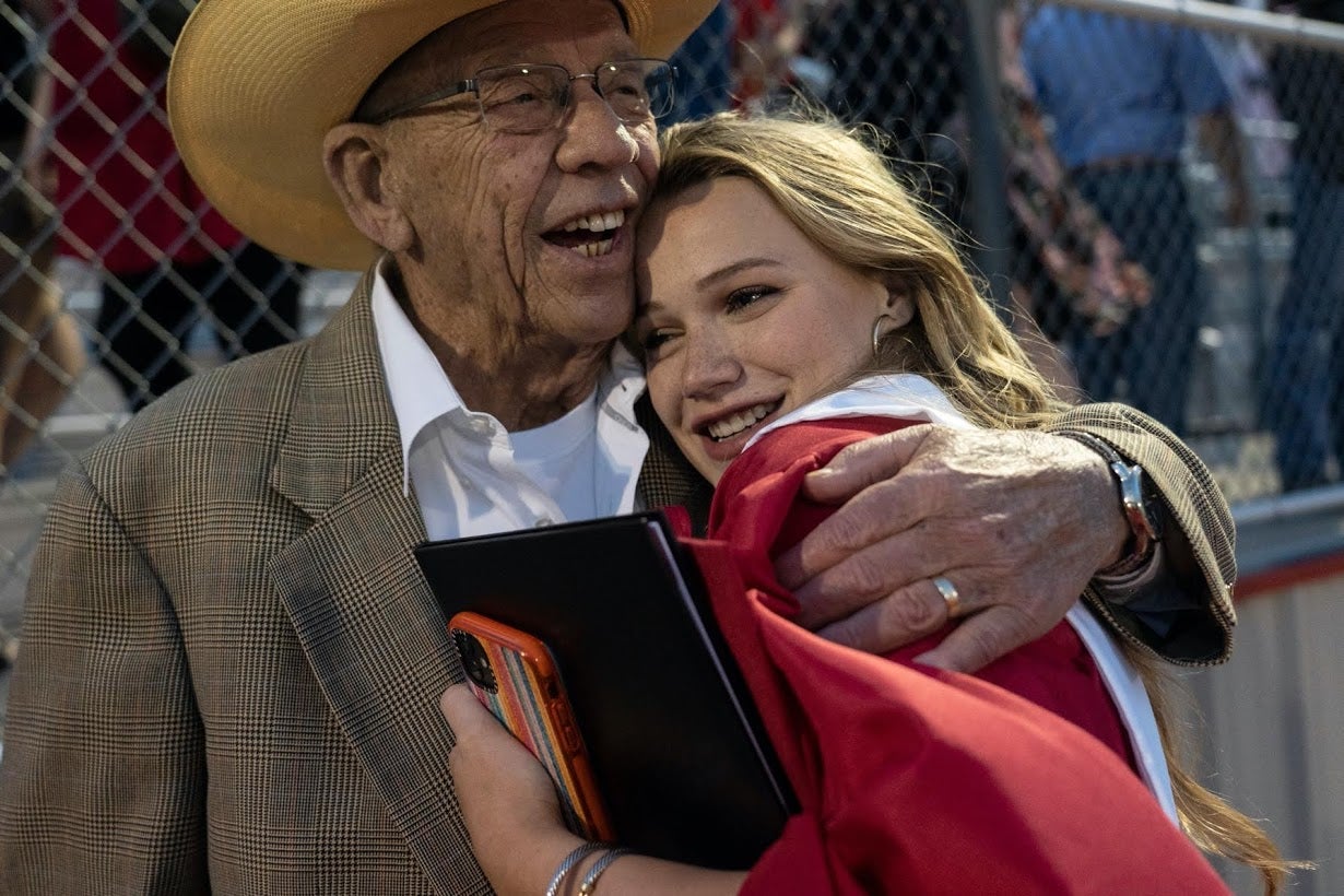 Munson is embraced by her grandfather Denny Belew after her graduation ceremony