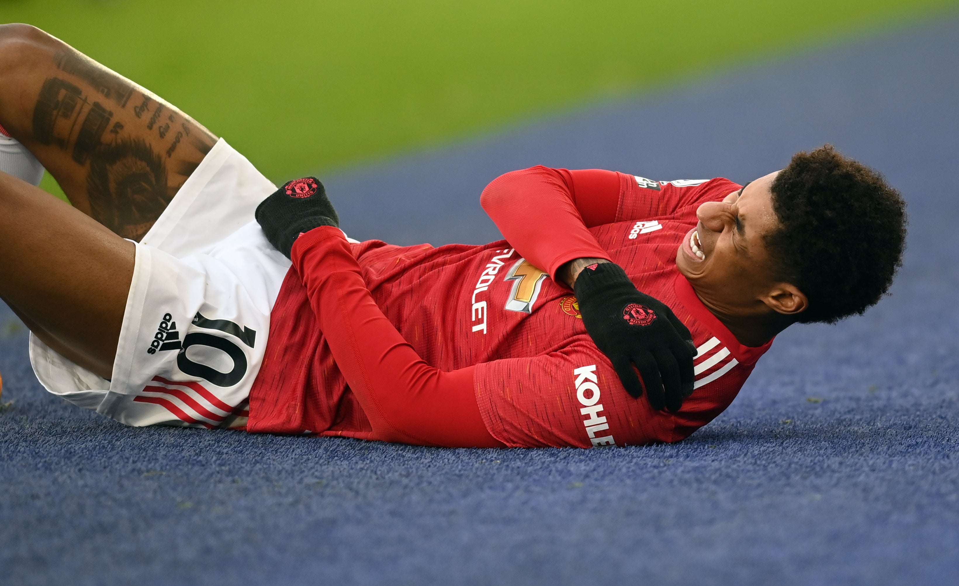 Marcus Rashford holds his shoulder in pain