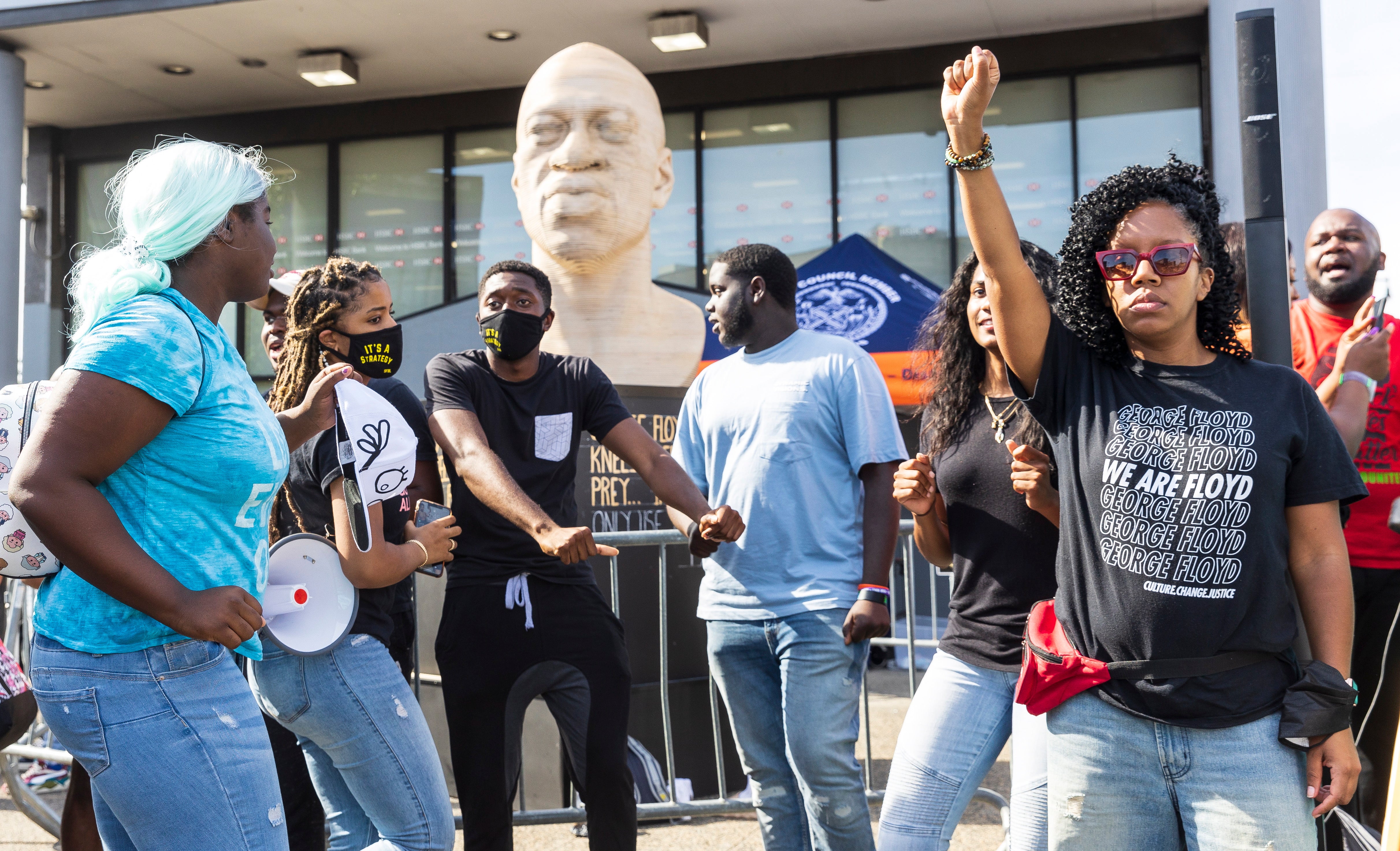 People gather near a recently unveiled statue of George Floyd following news that former Minnesota police officer Derek Chauvin was sentenced to 22 and 1/2 years in prison for Floyd's murder, in the Brooklyn borough of New York, 25 June 2021