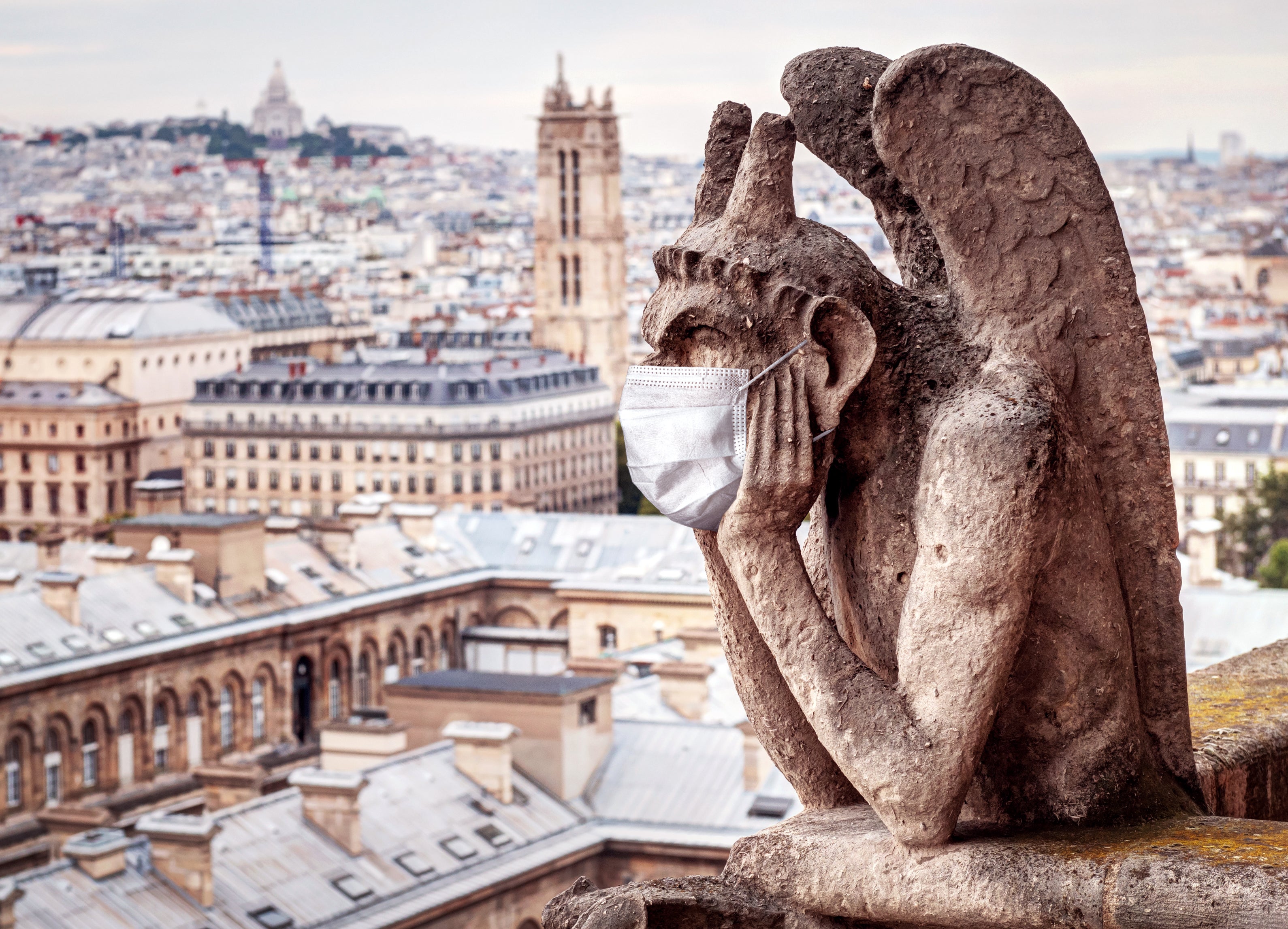 A face maks adorns a gargoyle on Notre Dame in Paris, France