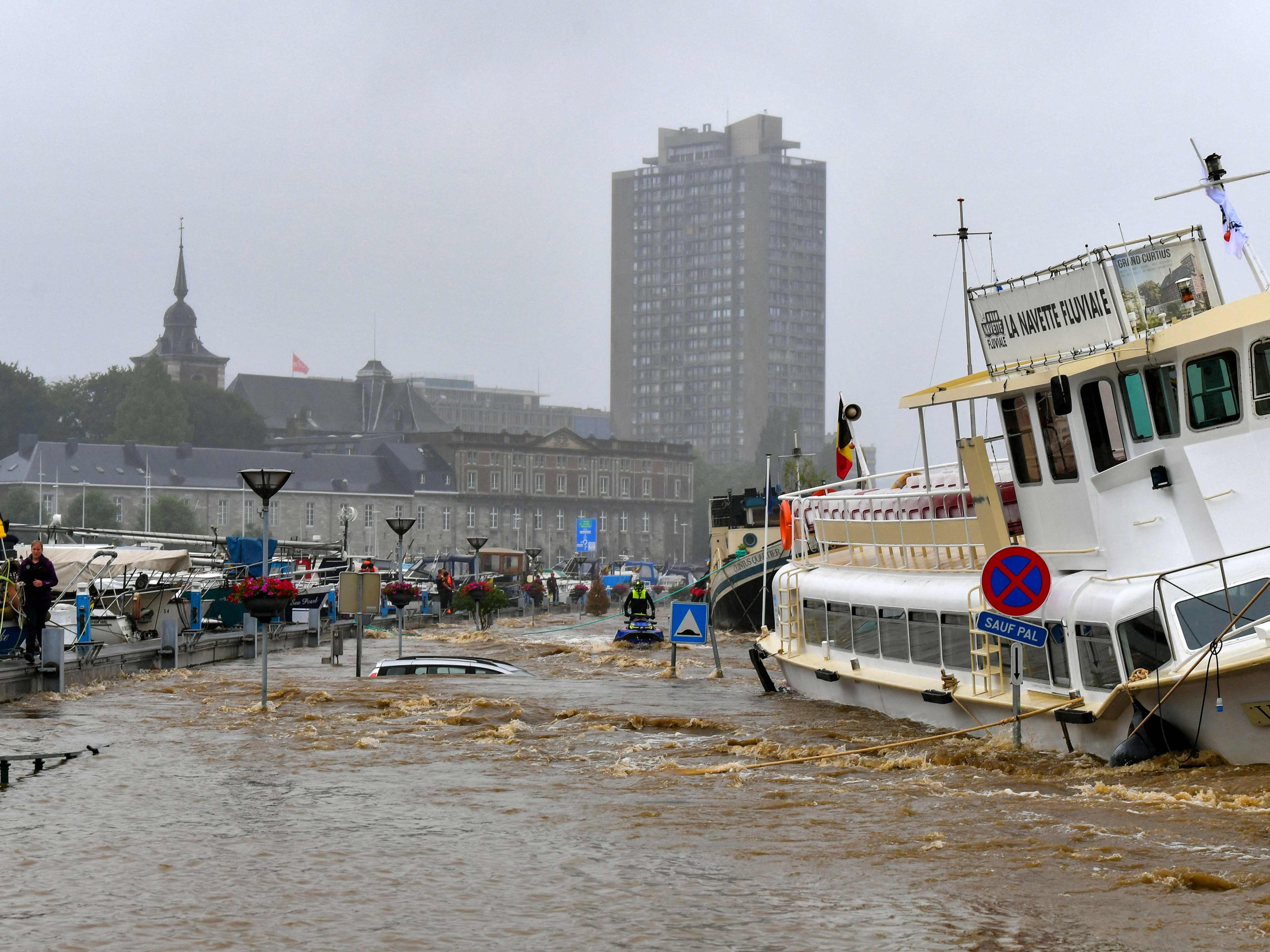 Members of the public stand next to a damaged boat after the floodings in Liege