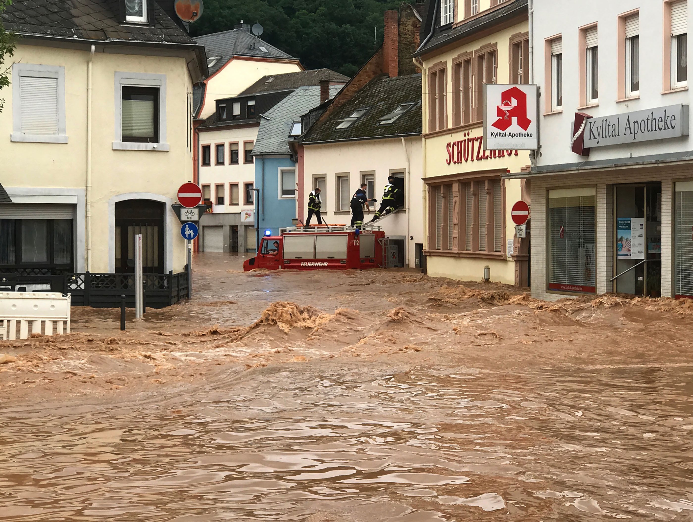 Fire fighters stand atop their vehicle as they climb into a house in the flooded village of Ehrang in Rhineland-Palatinate