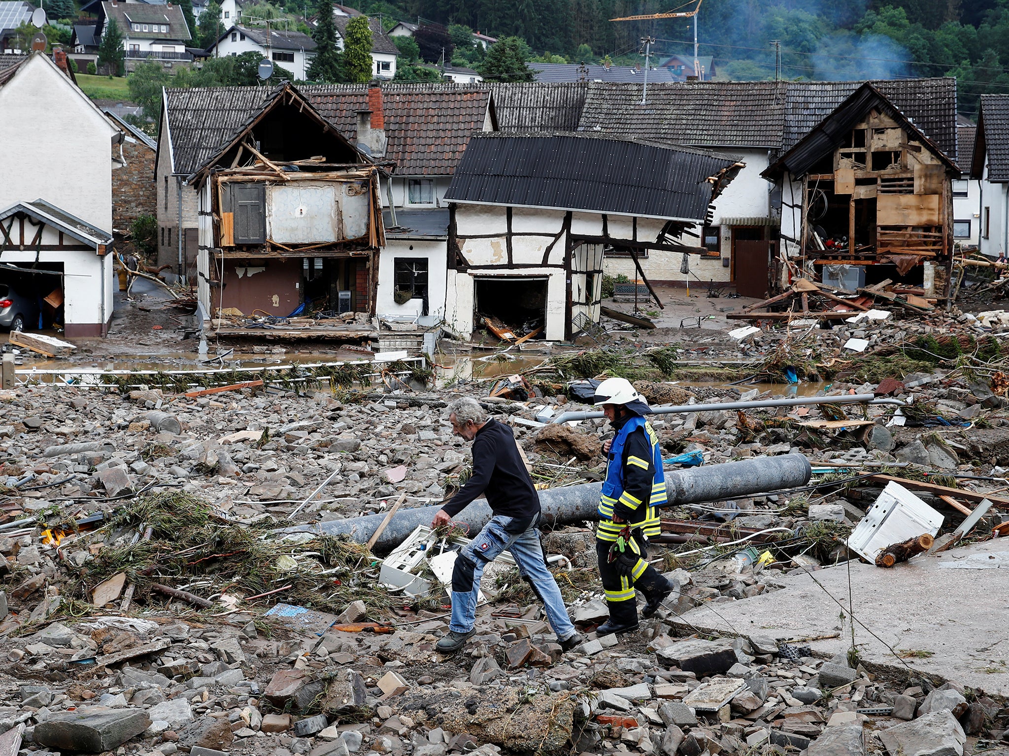 A man and firefighter walk through masses of debris following heavy rainfalls in Schuld, Germany