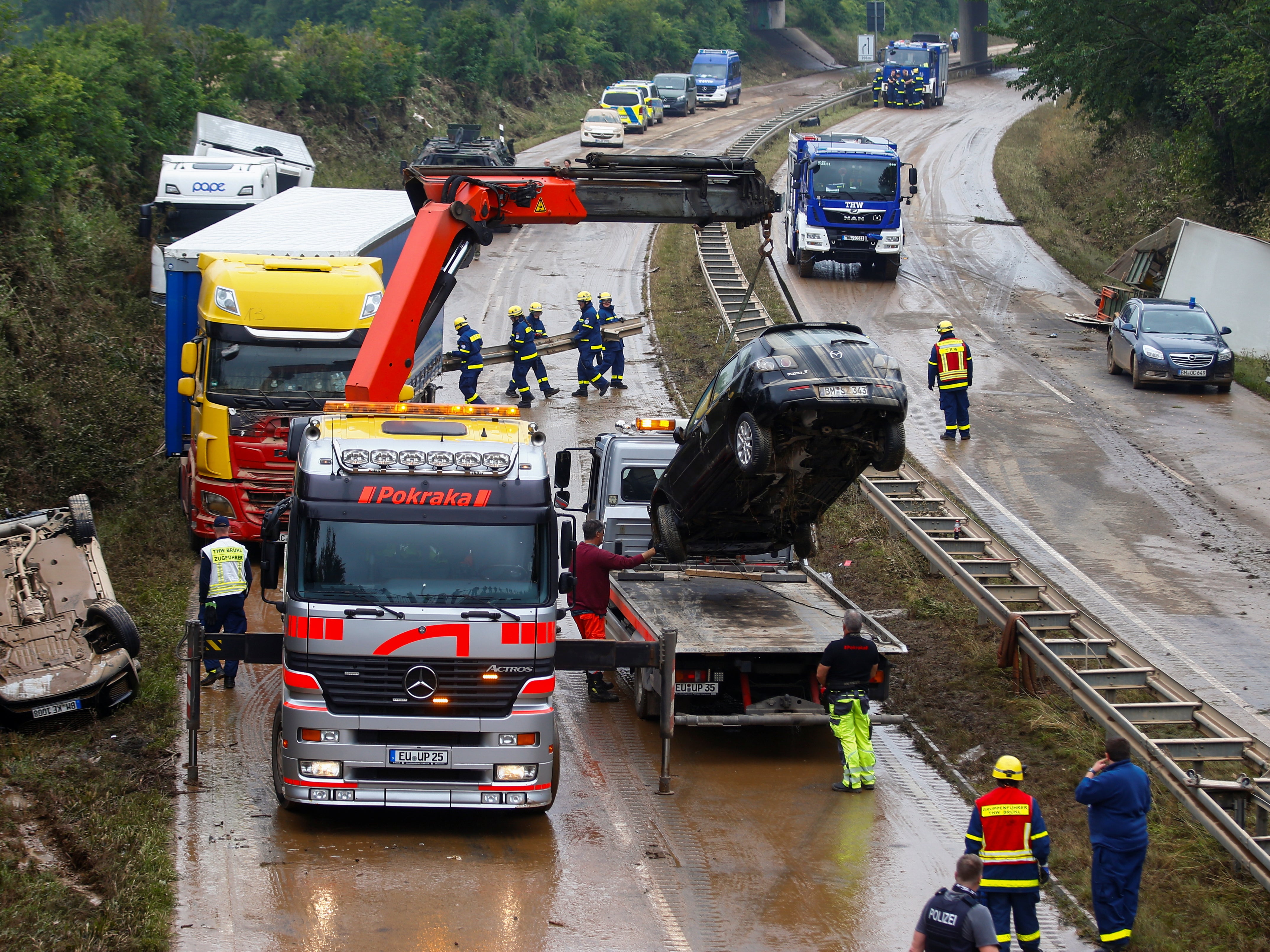 Workers recover vehicles stuck on the road following heavy rainfalls in Erftstadt, Germany