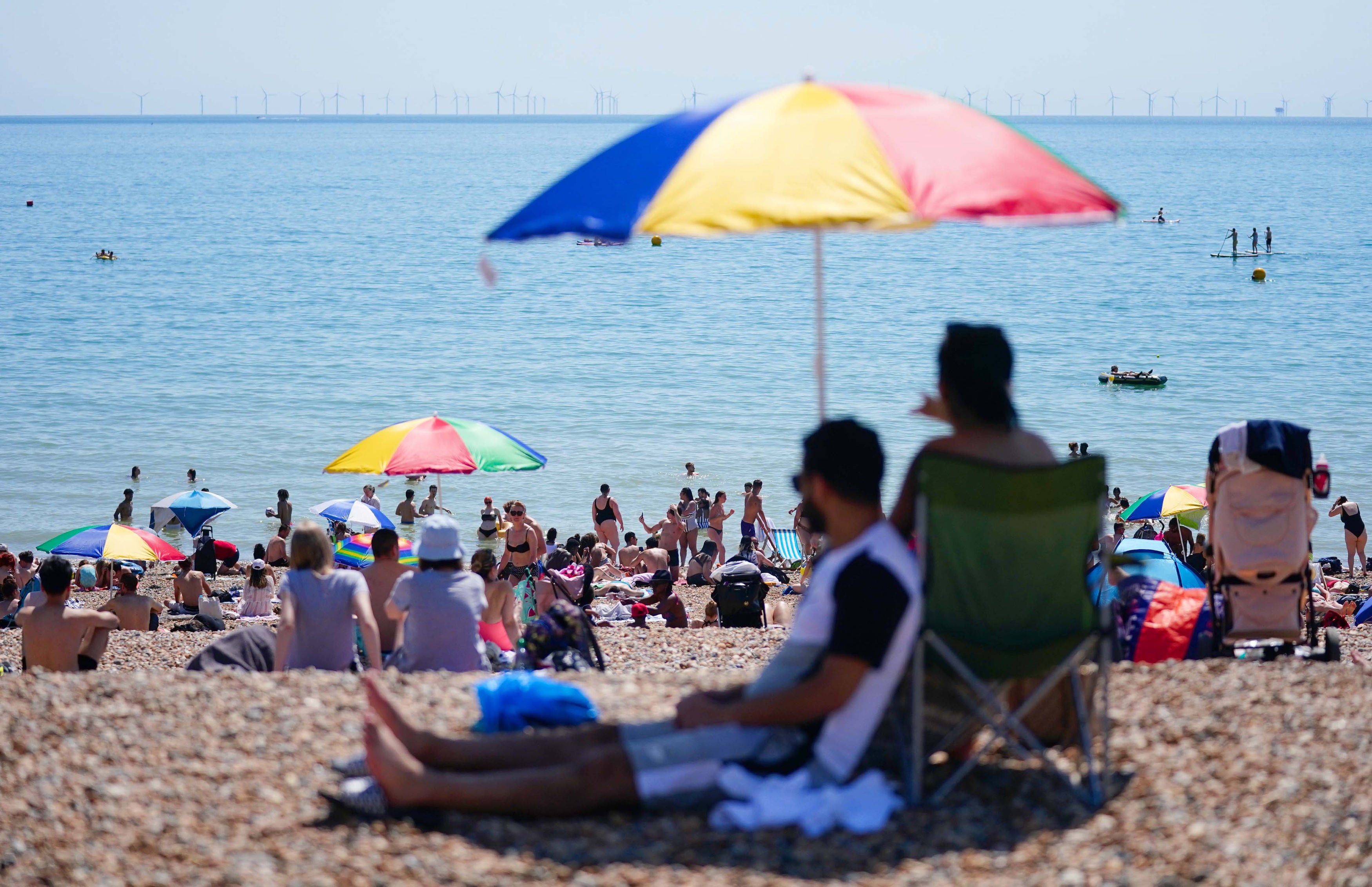 Beachgoers shelter underneath an umbrella on Brighton beach during the hottest day of the year so far