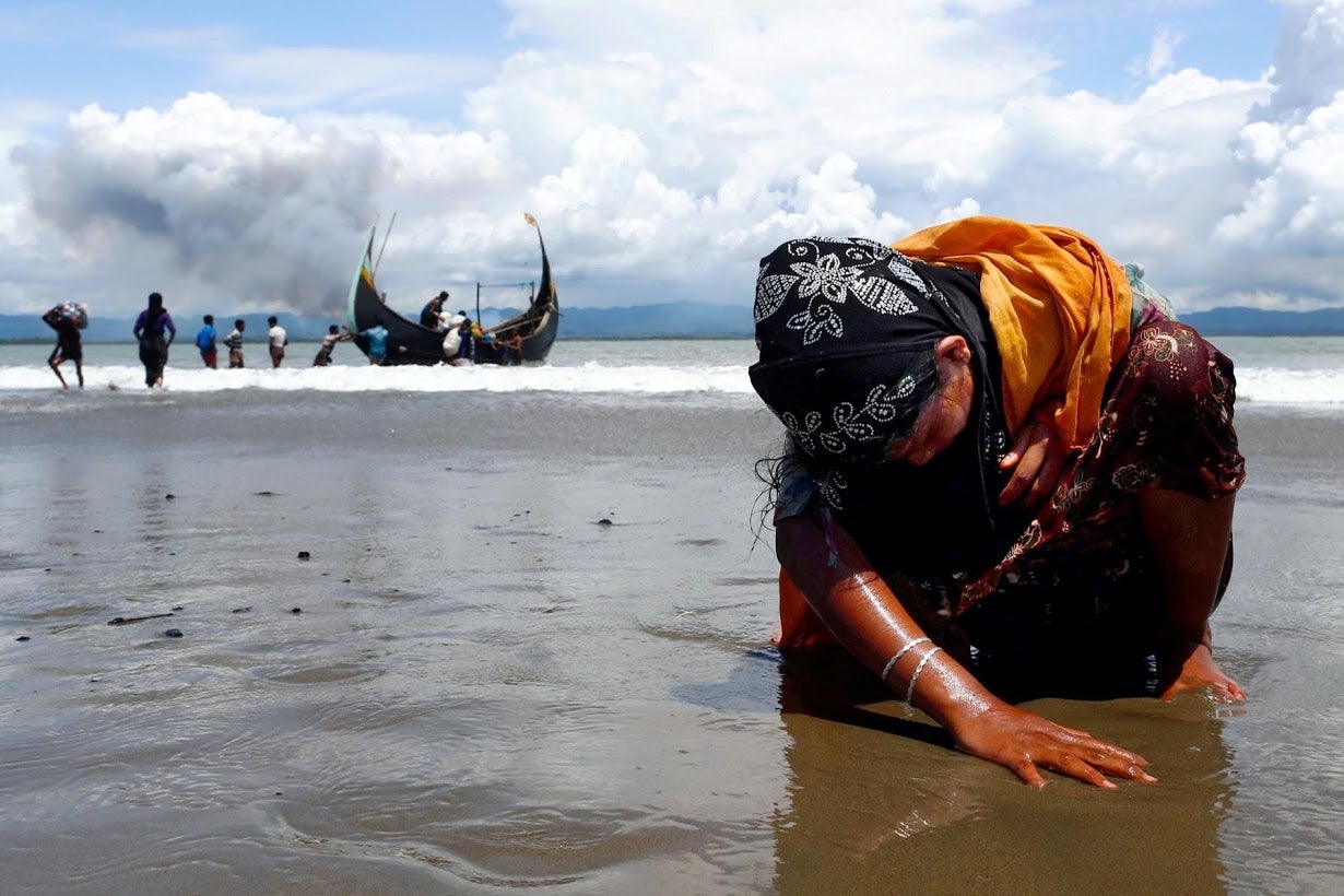 An exhausted Rohingya refugee touches the shore after crossing the Bangladesh-Myanmar border by boat through the Bay of Bengal in 2017