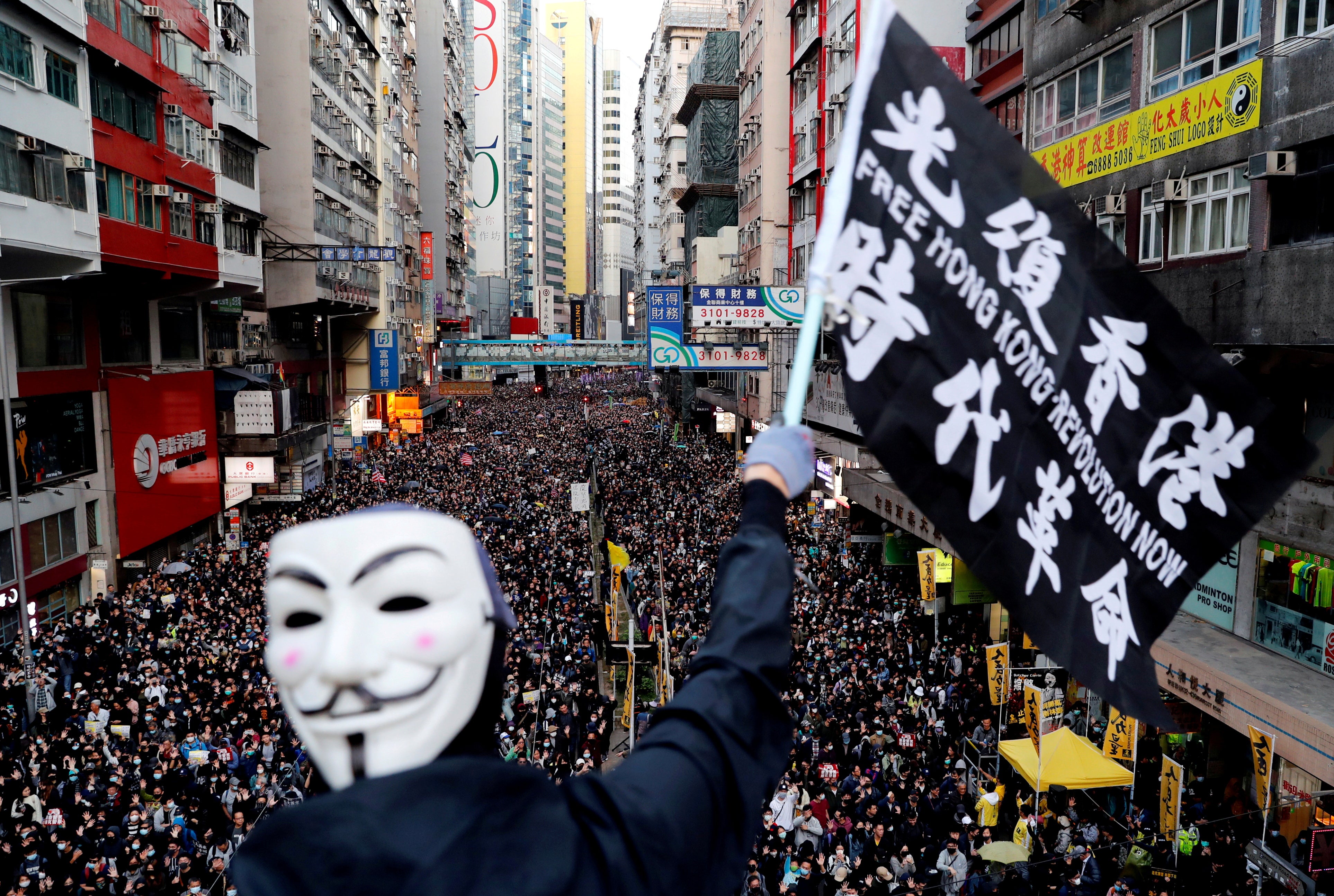 A protester wearing a Guy Fawkes mask waves a flag during a Human Rights Day march organised by the Civil Human Rights Front in Hong Kong in 2019