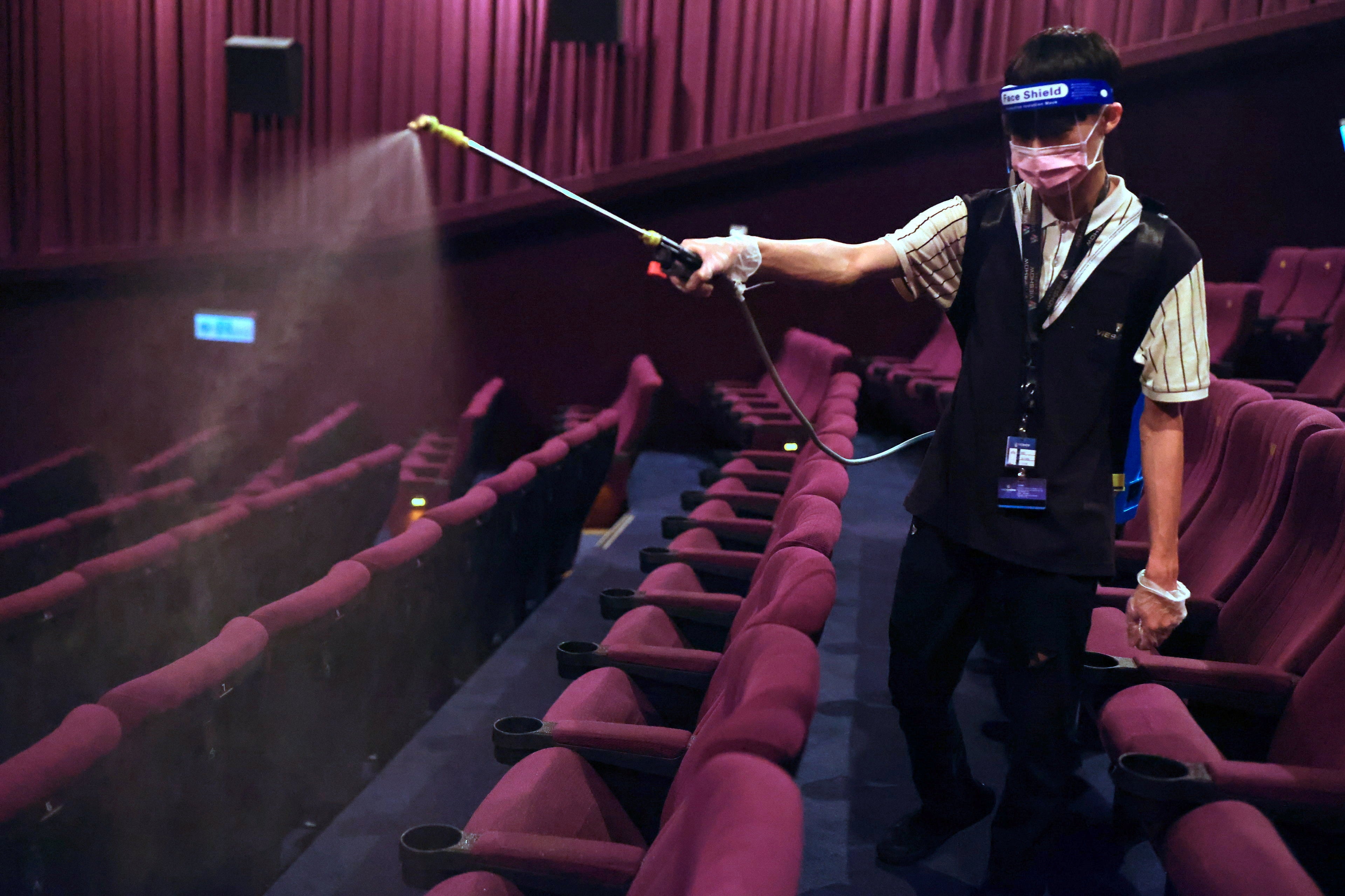 A staff disinfects the seats as cinemas reopen after Central Epidemic Command Center (CECC) eased coronavirus disease restrictions