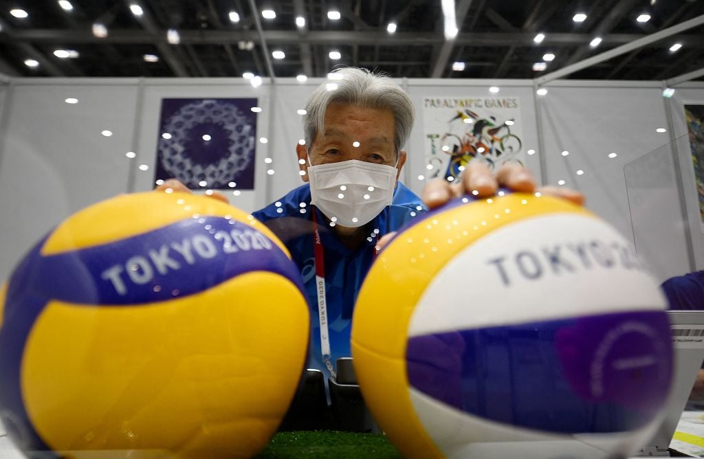 A volunteer wearing a face mask poses with volleyballs ahead of the Tokyo 2020 Olympic Games