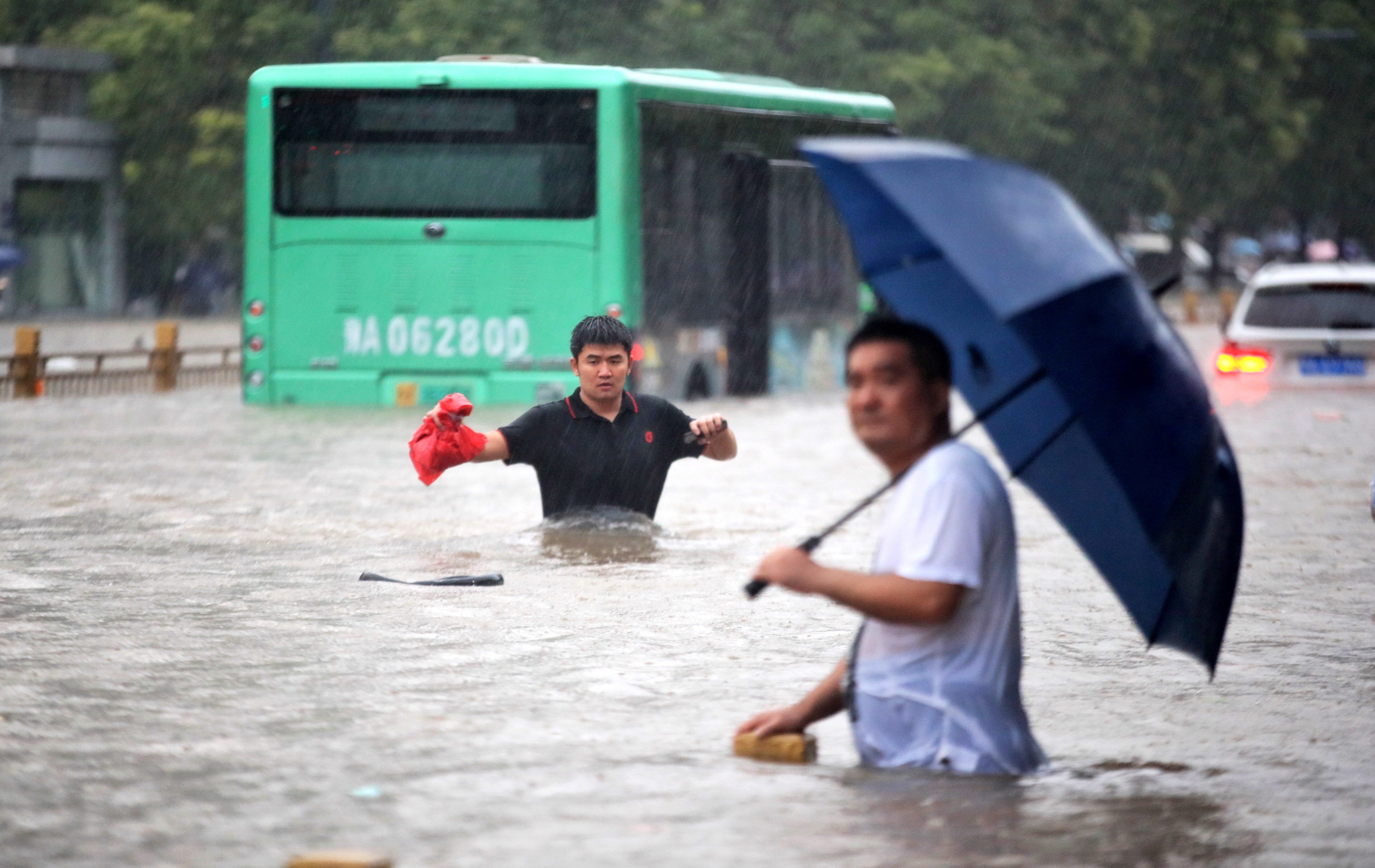 Two men walk along a flooded road in Zhengzhou city, China, on 20 July, 2021.