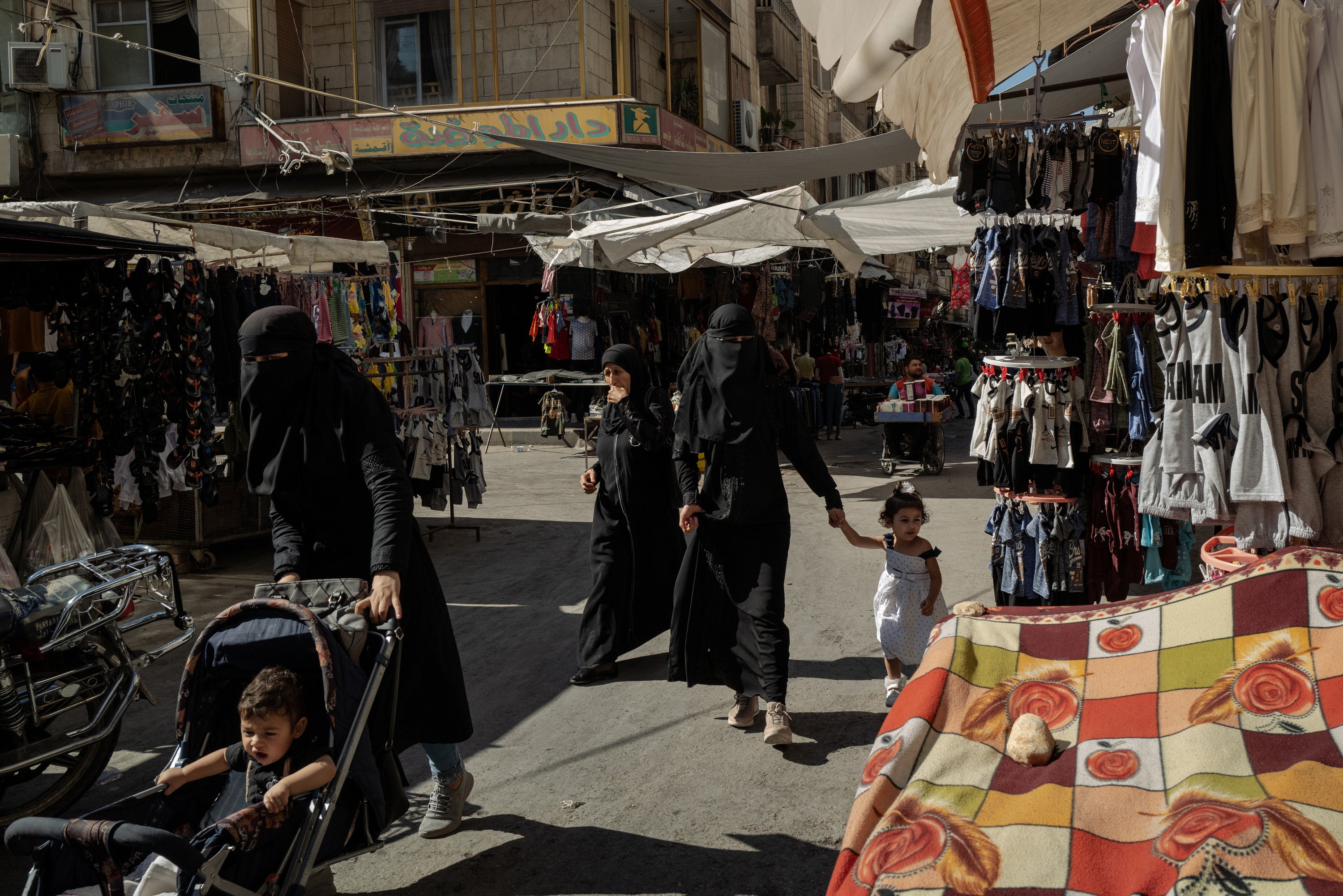 Women walk through a souk in Idlib