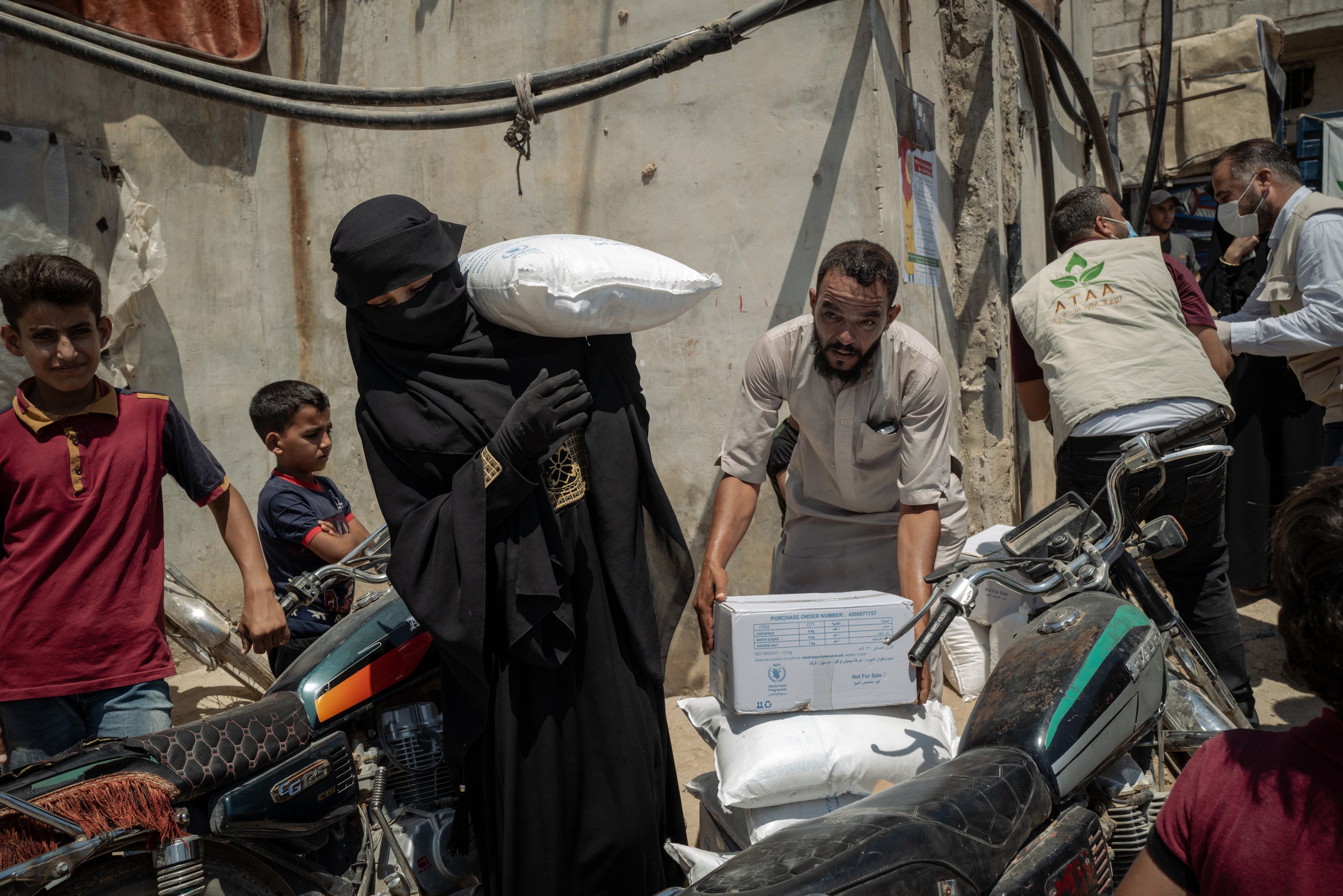 A woman carries a bag of food at a settlement for internally displaced people near Atma, in northern Idlib province