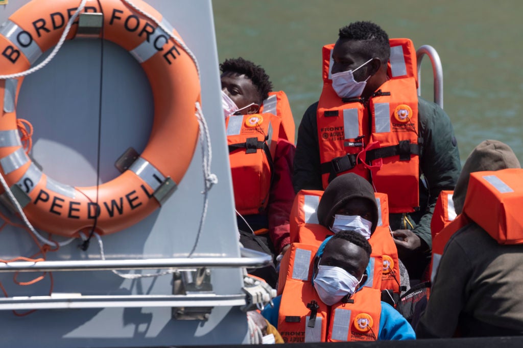 Border Force officials guide newly arrived migrants to a holding facility after being picked up in the Channel