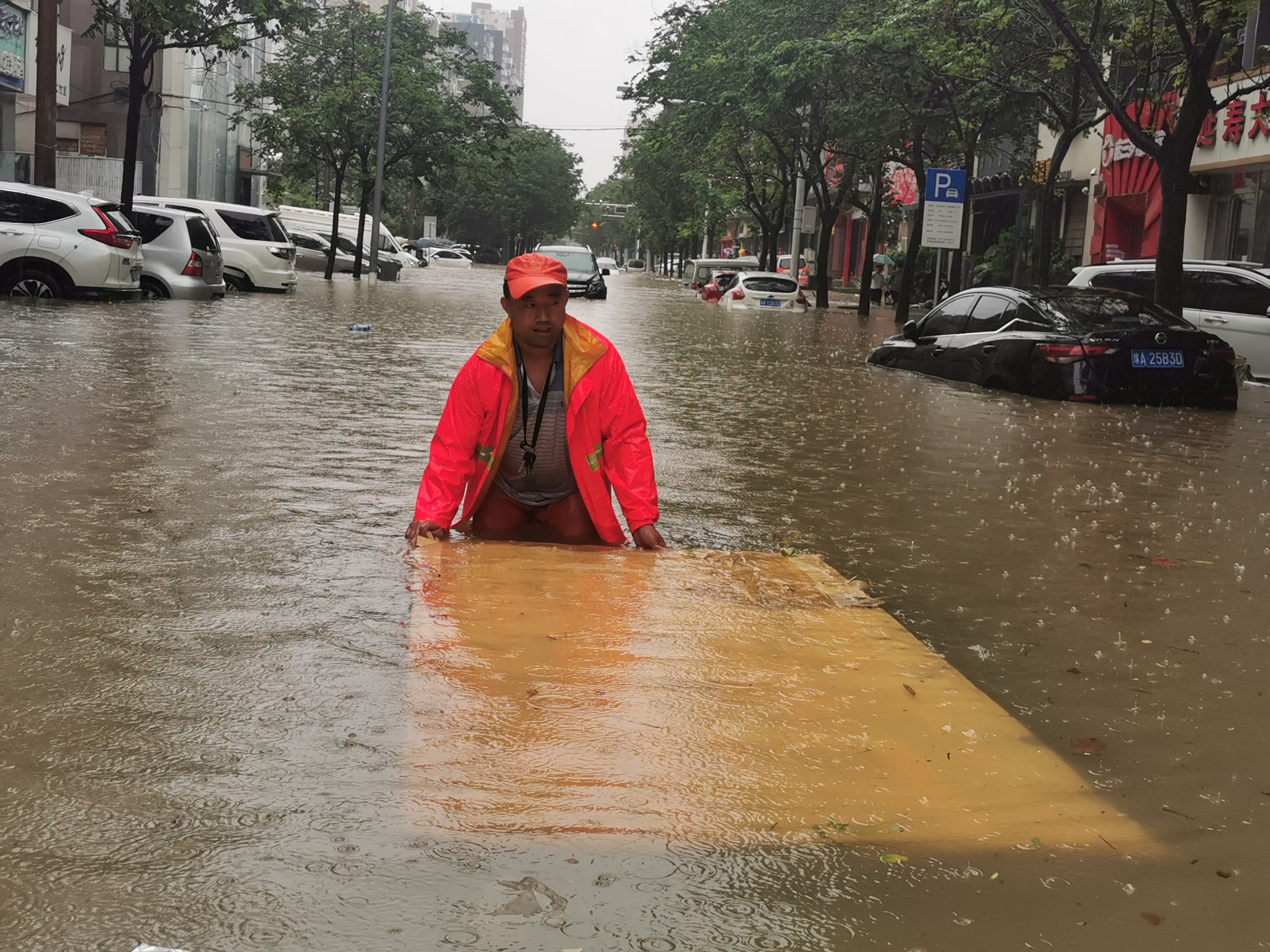 A sanitation worker cleans rubbish from a flooded street on Wednesday in Zhengzhou, Henan province