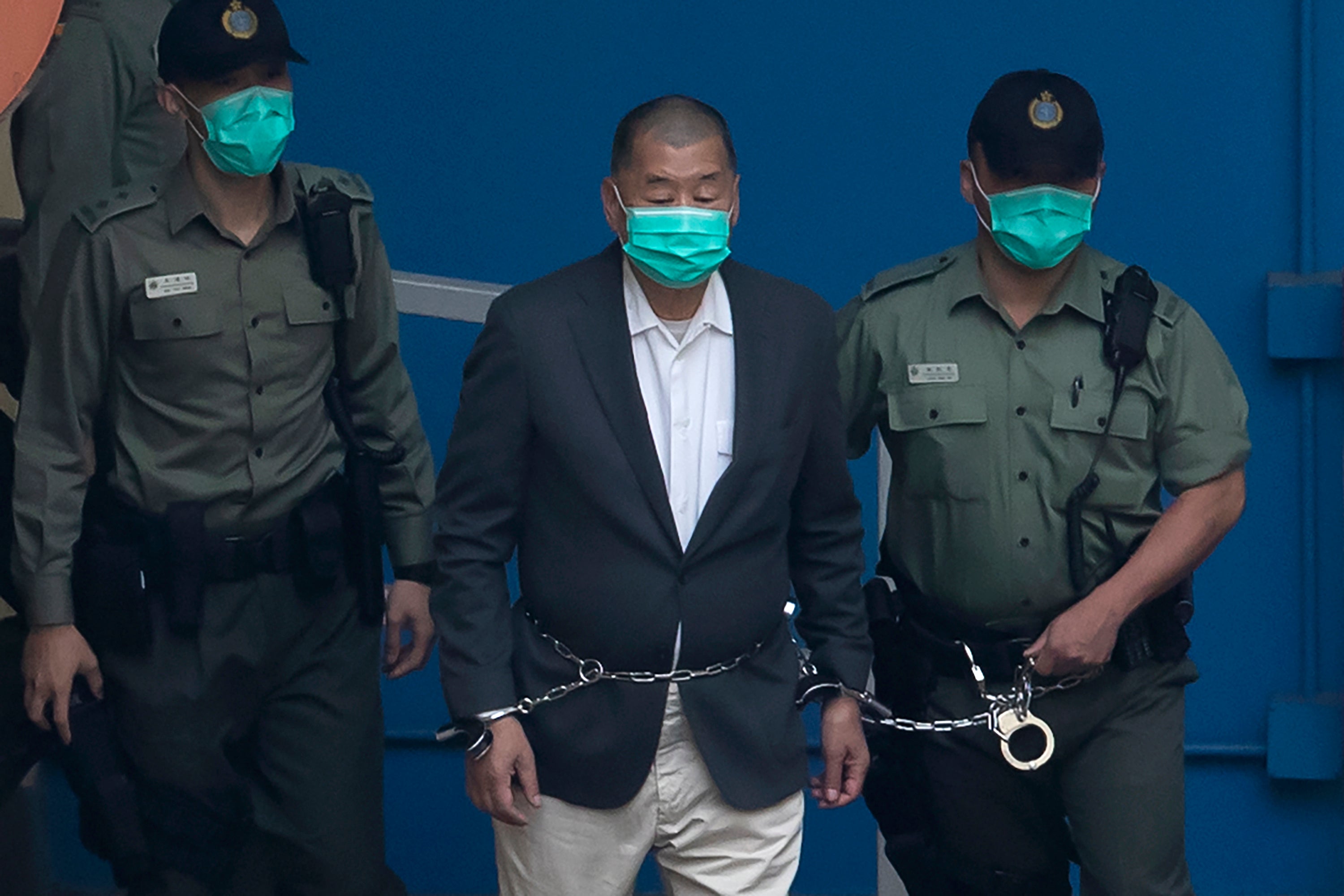 Jimmy Lai, who founded the Apple Daily, is escorted by Correctional Services officers to get on a prison van before appearing in a court in Hong Kong