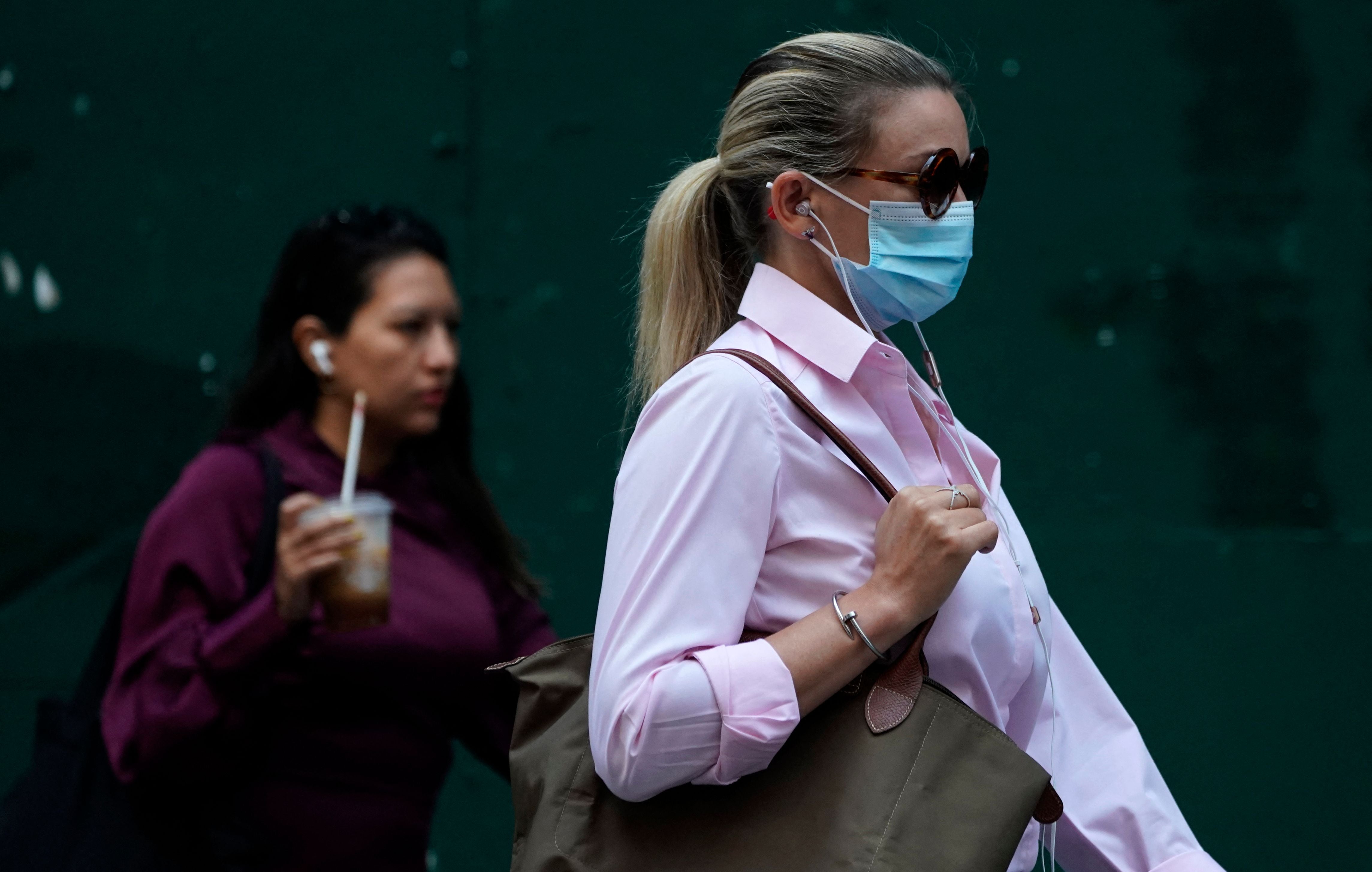 People walk through Times Square on 22 July 2021, as the Delta Covid surge is renewing calls for mask mandates in New York