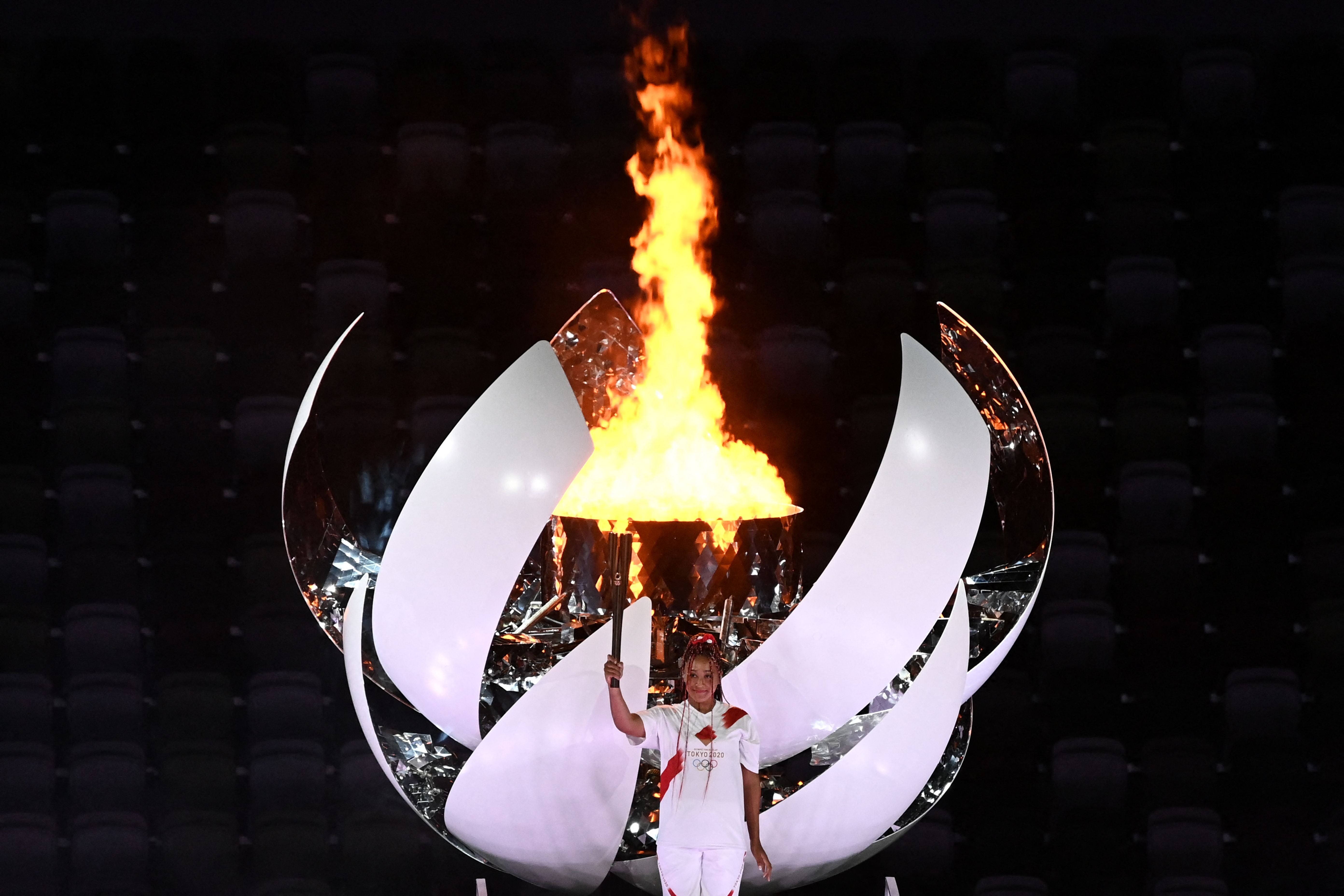 Japanese tennis player Naomi Osaka holds the Olympic Torch after lighting the flame of hope in the Olympic Cauldron during the opening ceremony