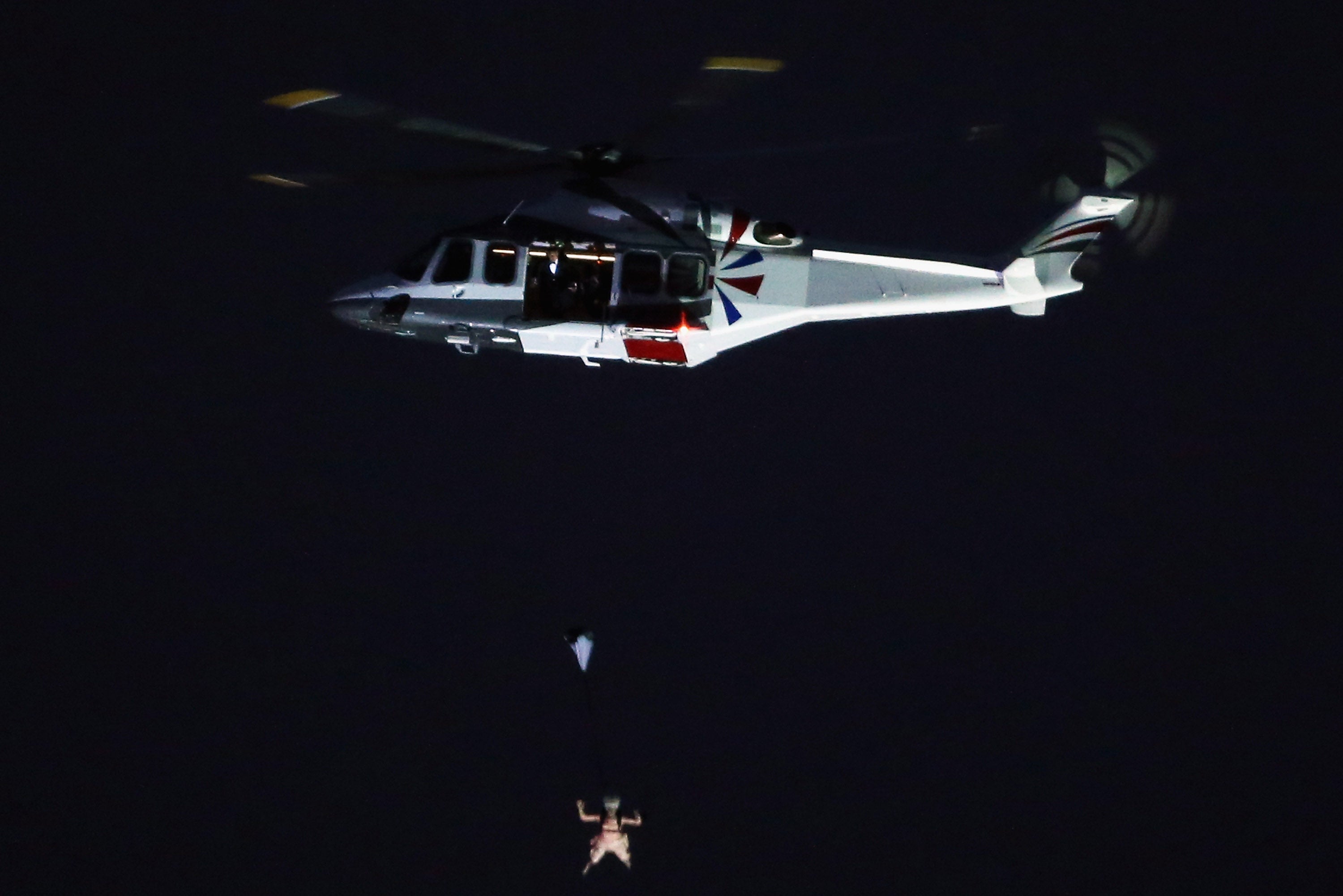 A person dressed as Queen Elizabeth parachutes into the Olympics stadium