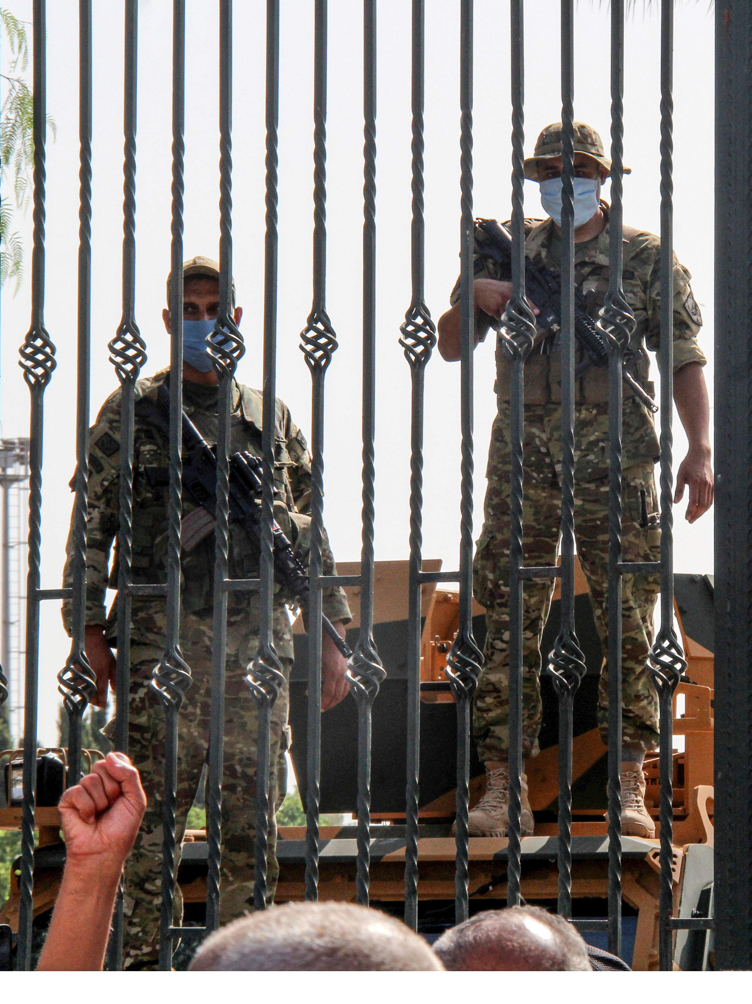 Tunisian soldiers guard the main entrance of the parliament as demonstrators gather outside the gate in Tunis