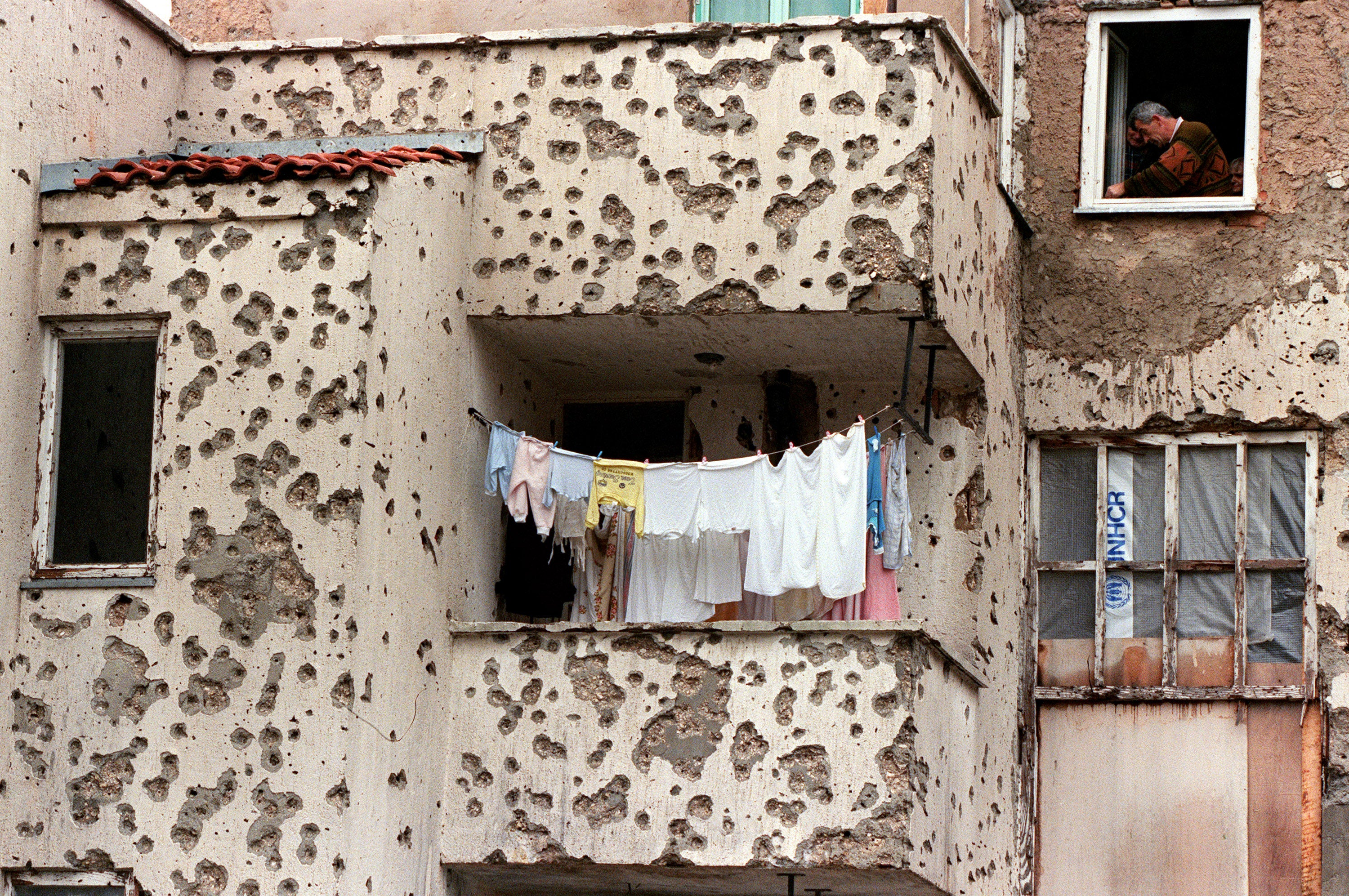 A resident tries to fix up a window of his flat in a bullet-riddled building in the eastern district of Mostar, southern Bosnia, 21 December 1995