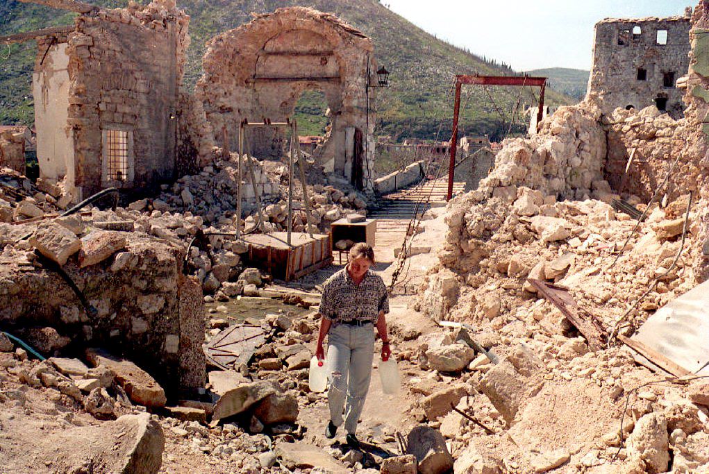 A girl carries jugs of water down a street destroyed by Croat shelling near the old bridge in the eastern (Muslim) part of Mostar, 30 March 1994