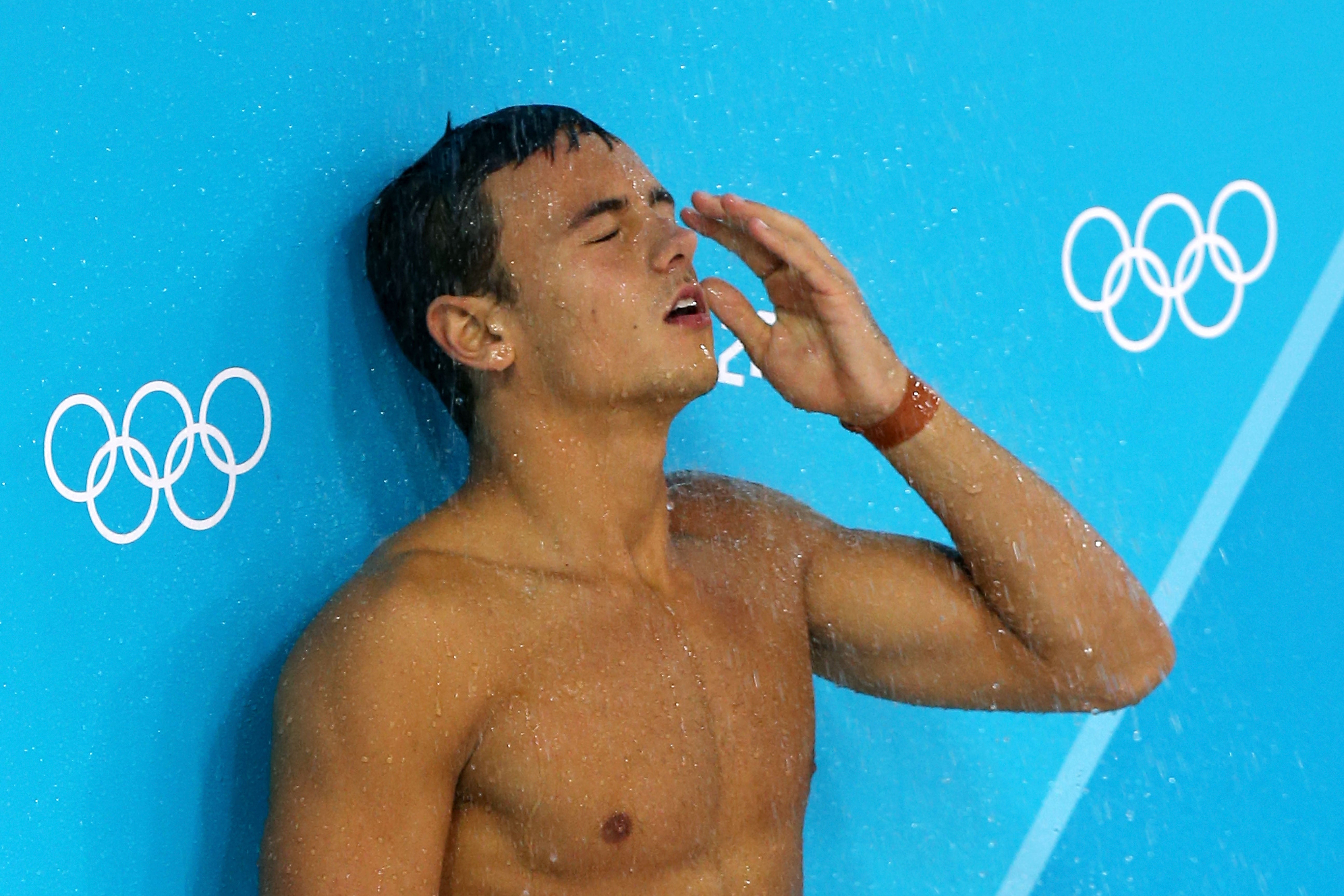 Tom Daley of Great Britain stands under a pool deck shower during the Men's Synchronised 10m Platform Diving on Day 3 of the London 2012 Olympic Games at the Aquatics Centre on July 30, 2012 in London, England.