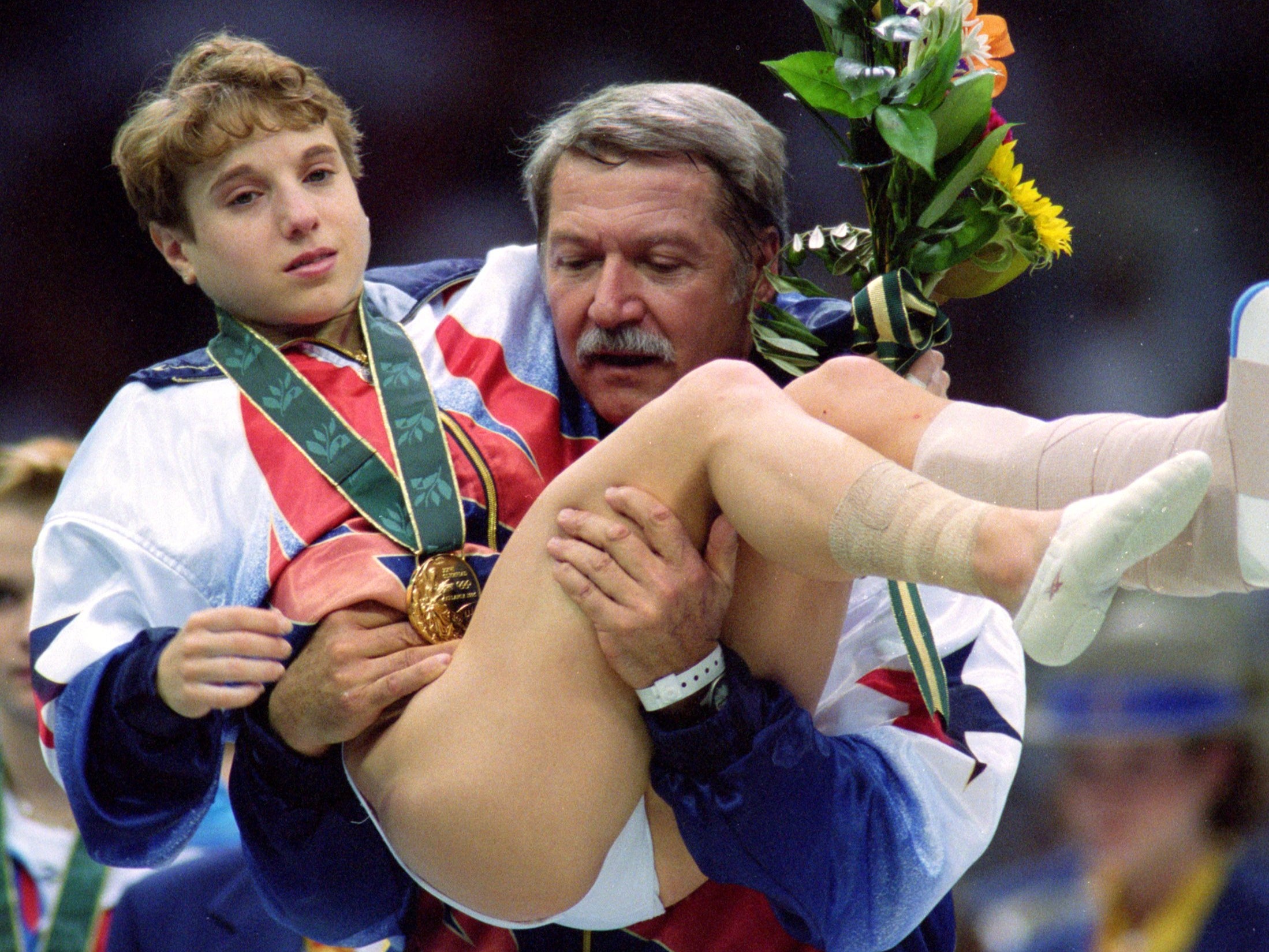 File: Kerri Strug being carried off the floor by her coach Bela Karolyi after her performance at the 1996 Olympic Games in Atlanta, Georgia