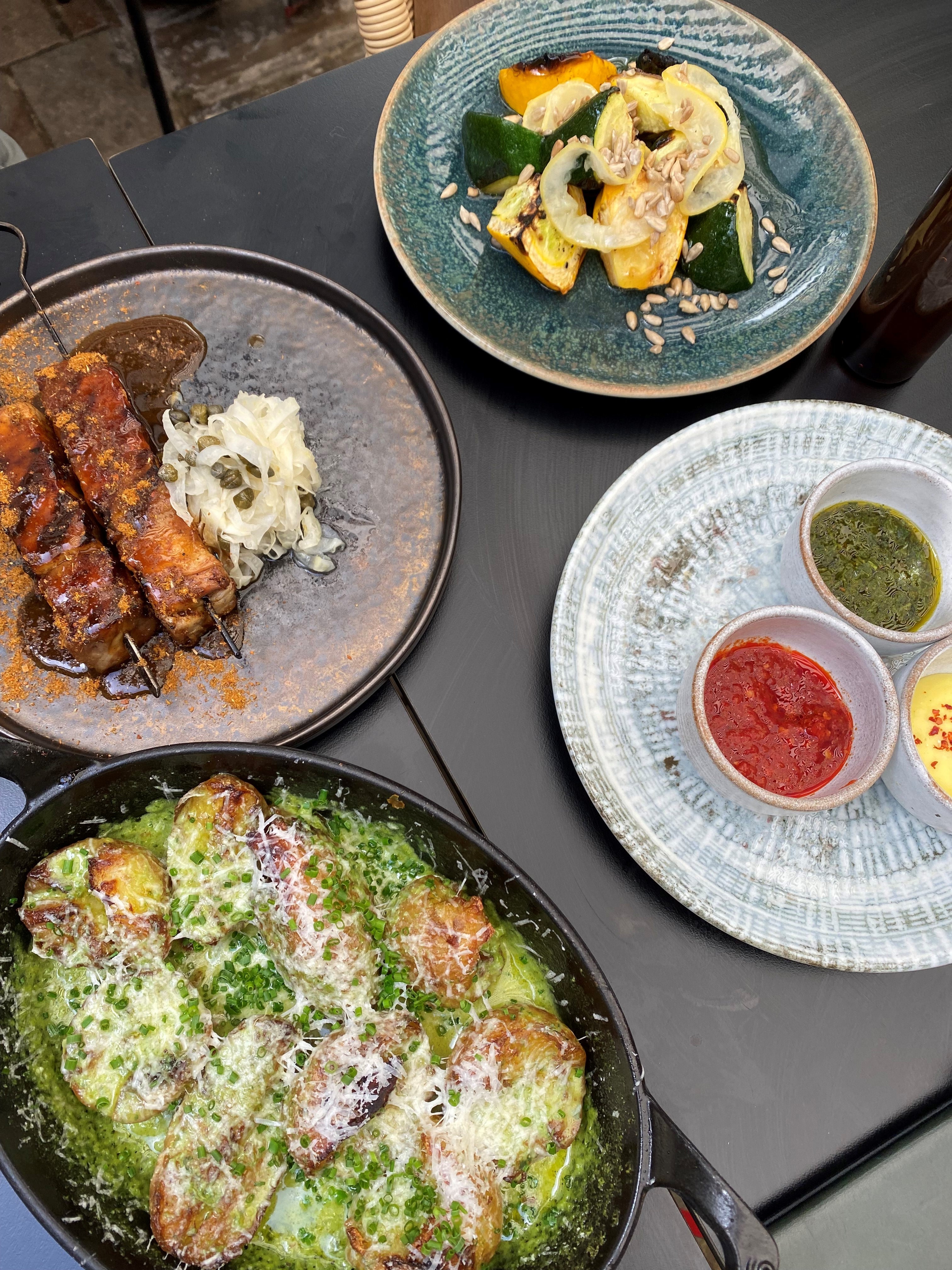 Clockwise from bottom left: herby, cheesy baked potatoes; pork belly shawarma; heritage courgettes; and dips