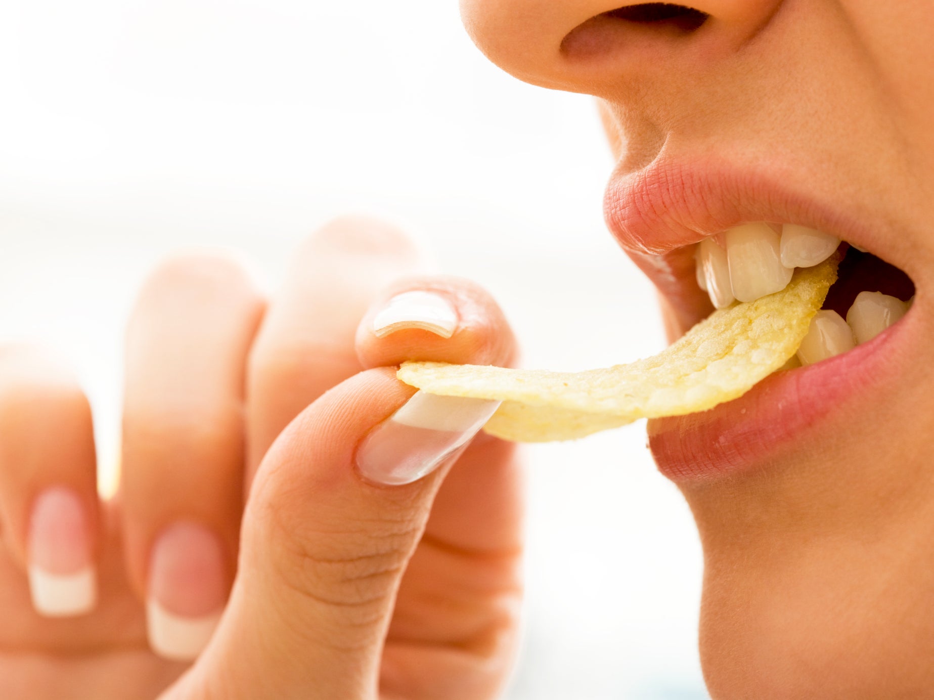 A person takes a bite of a crisp