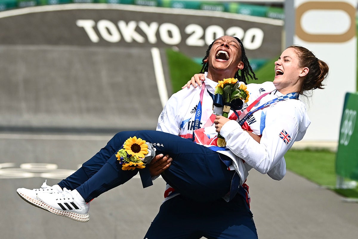 Beth Shriever is lifted by Kye Whyte after the BMX cyclists won gold and silver medals in their Olympic finals