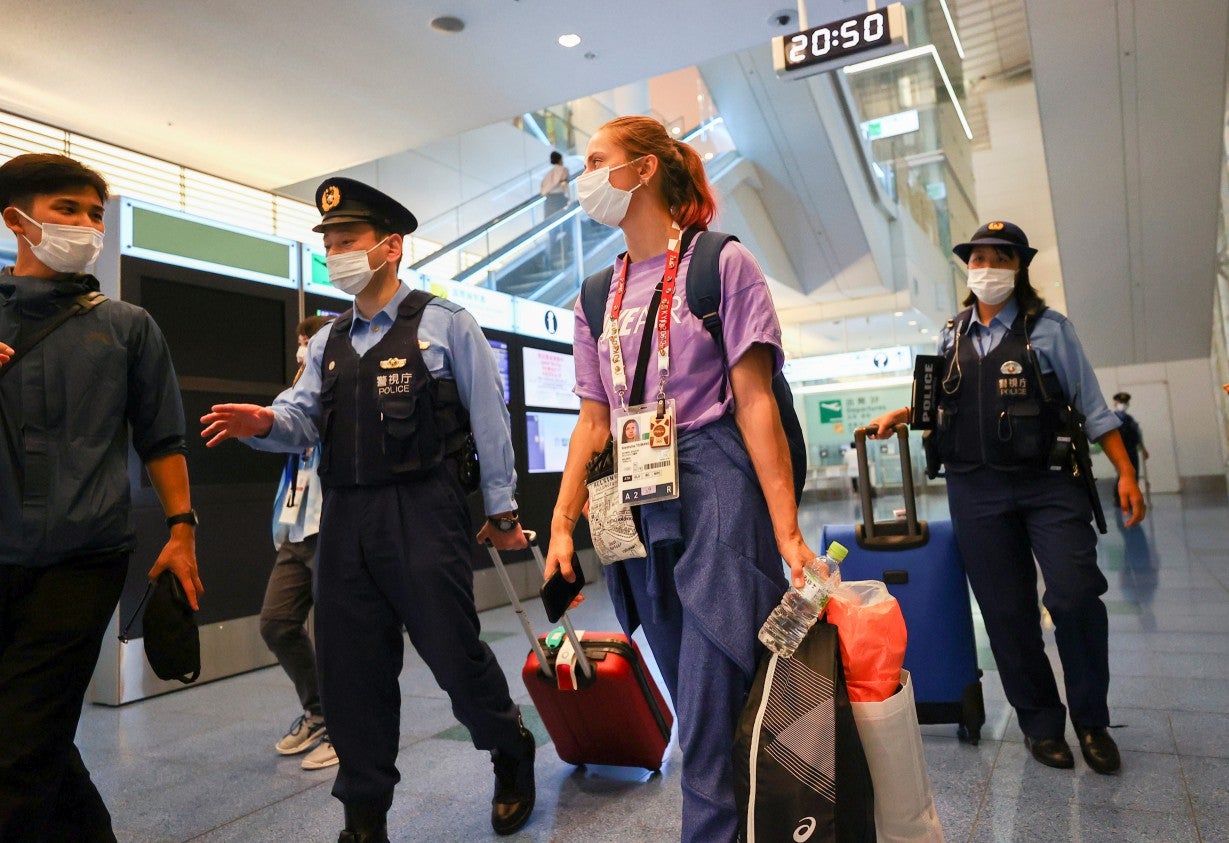 <p>Belarusian athlete Krystsina Tsimanouskaya is escorted by police officers at Haneda international airport in Tokyo</p>