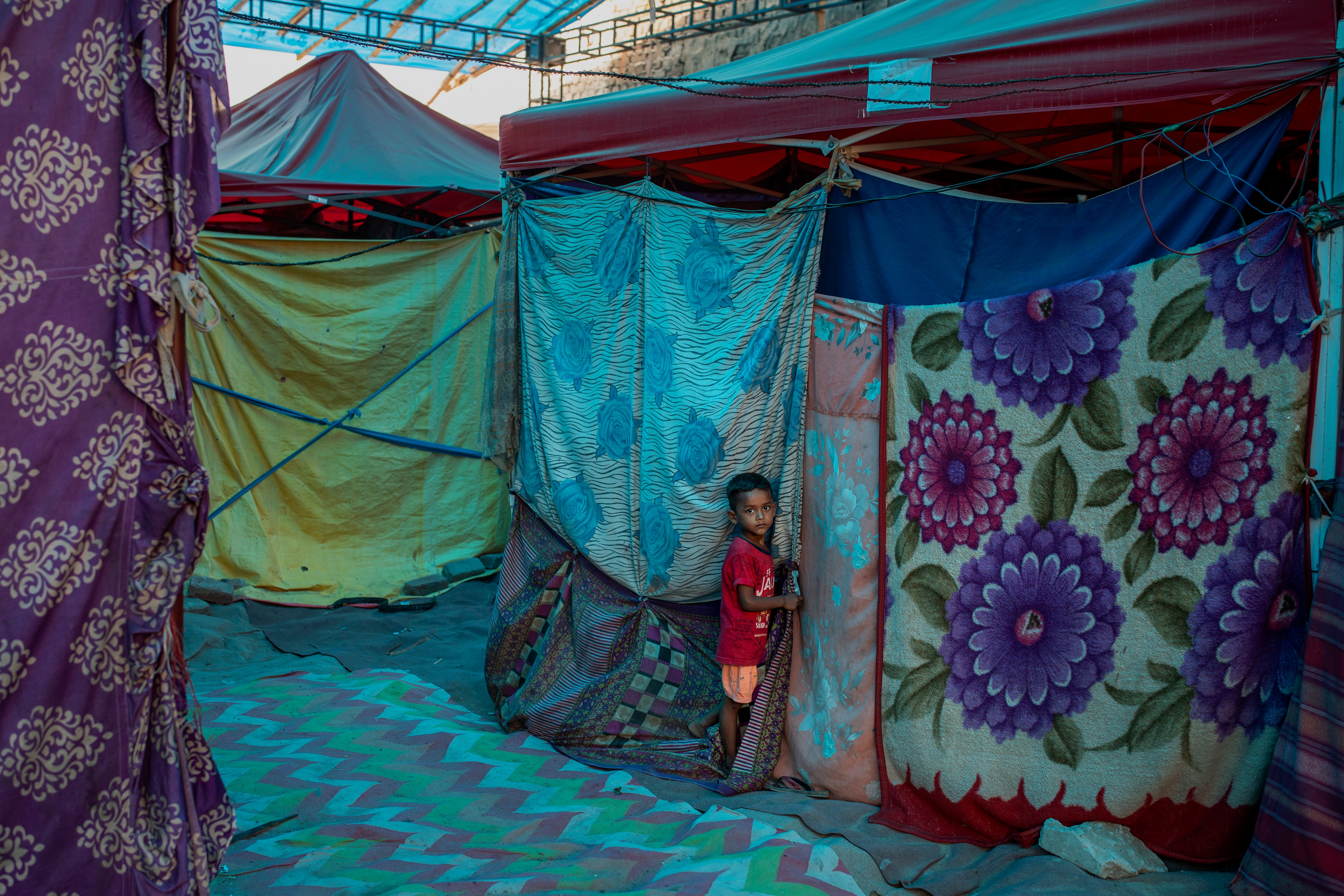 A young Rohingya boy stands outside a tent at a refugee camp alongside the banks of the Yamuna river in New Delhi on 1 July