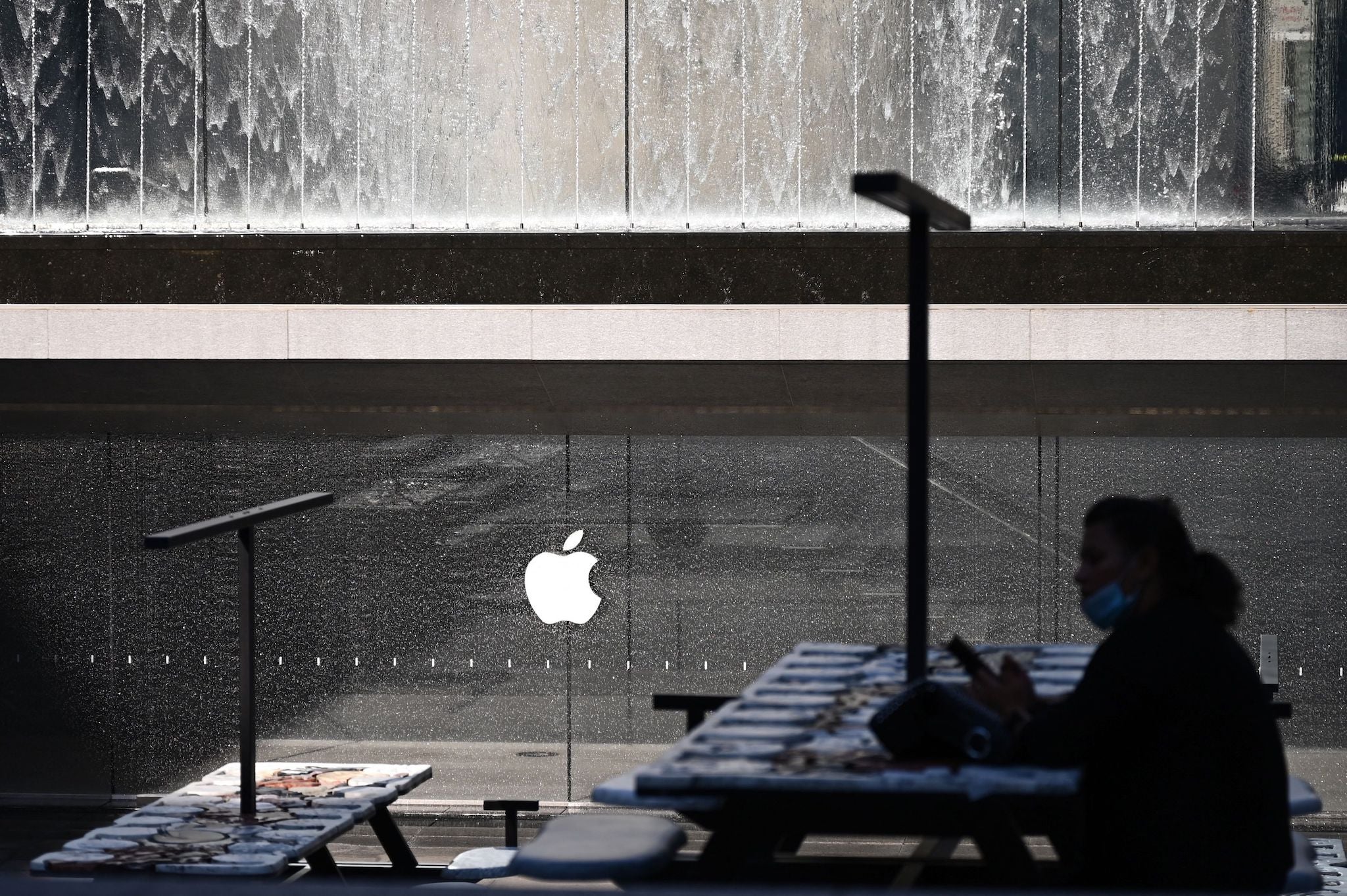 A woman is silhouetted near the installation The Moral of the Story, by French artist Neïl Beloufa, near the Apple Store in Piazza Liberty in Milan, on July 7, 2021