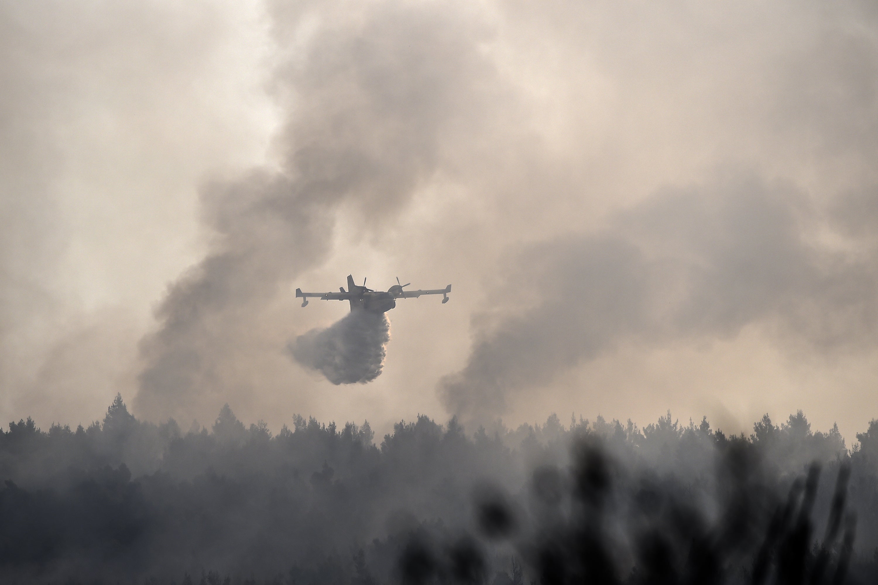 A firefighting plane battles against the fires in the area of Varibobi in Acharnes, north of Athens