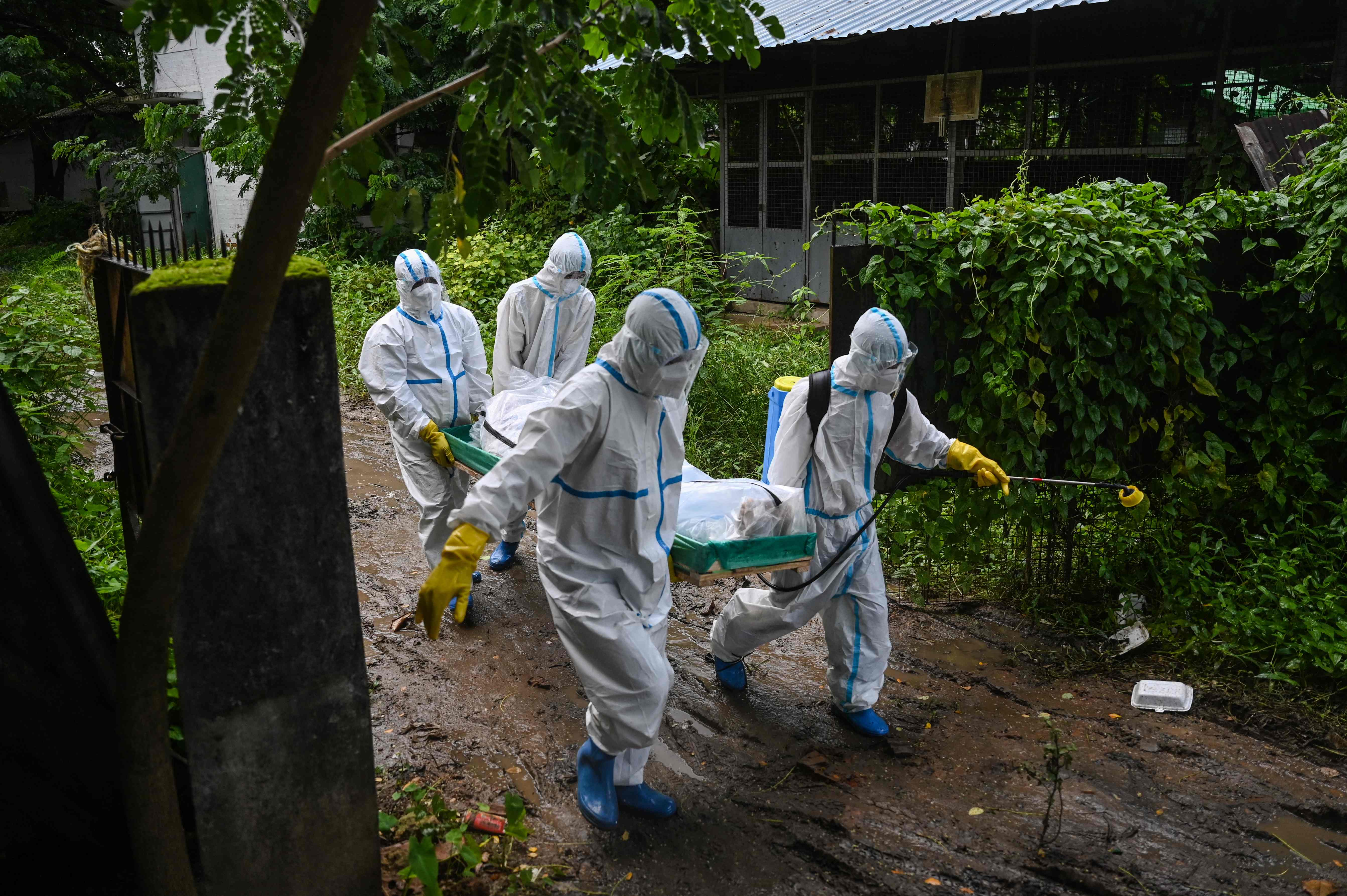 Volunteers wearing PPE carry the body of a victim of Covid-19 to a cemetery in Hlegu Township in Yangon